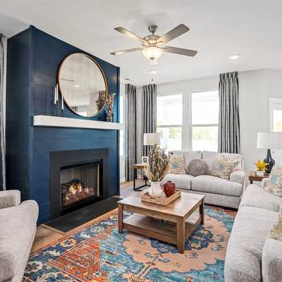 Cozy living room at Sage Farms in White House TN with navy blue fireplace, round mirror, plush sofas and patterned rug