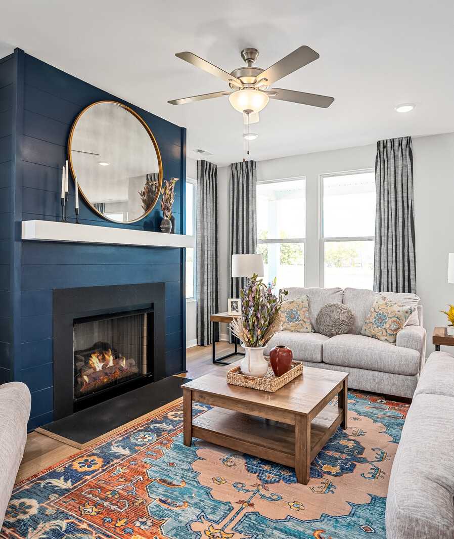Cozy living room at Sage Farms in White House TN with navy blue fireplace, round mirror, plush sofas and patterned rug