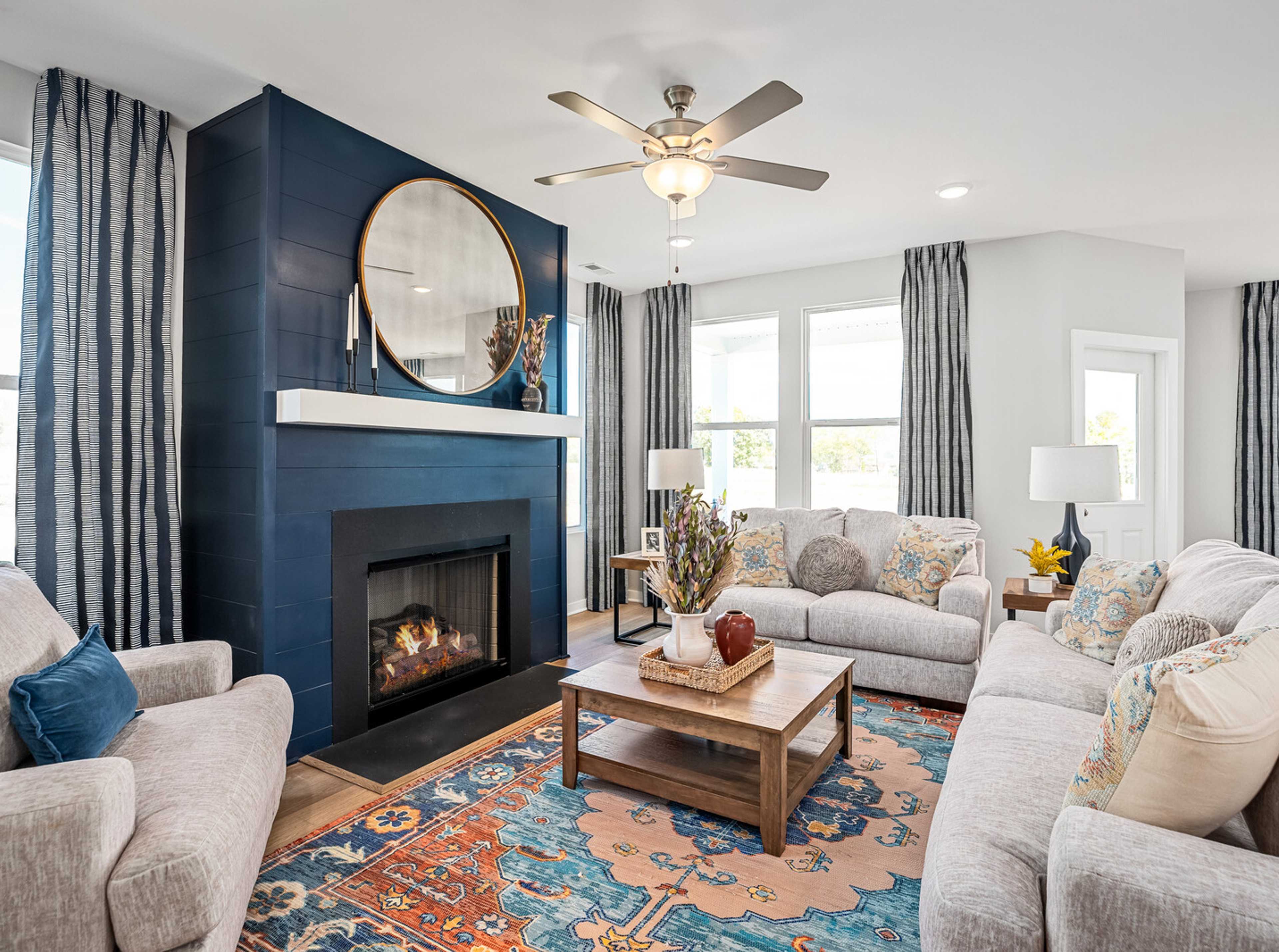 Cozy living room at Sage Farms in White House TN with navy blue fireplace, round mirror, plush sofas and patterned rug