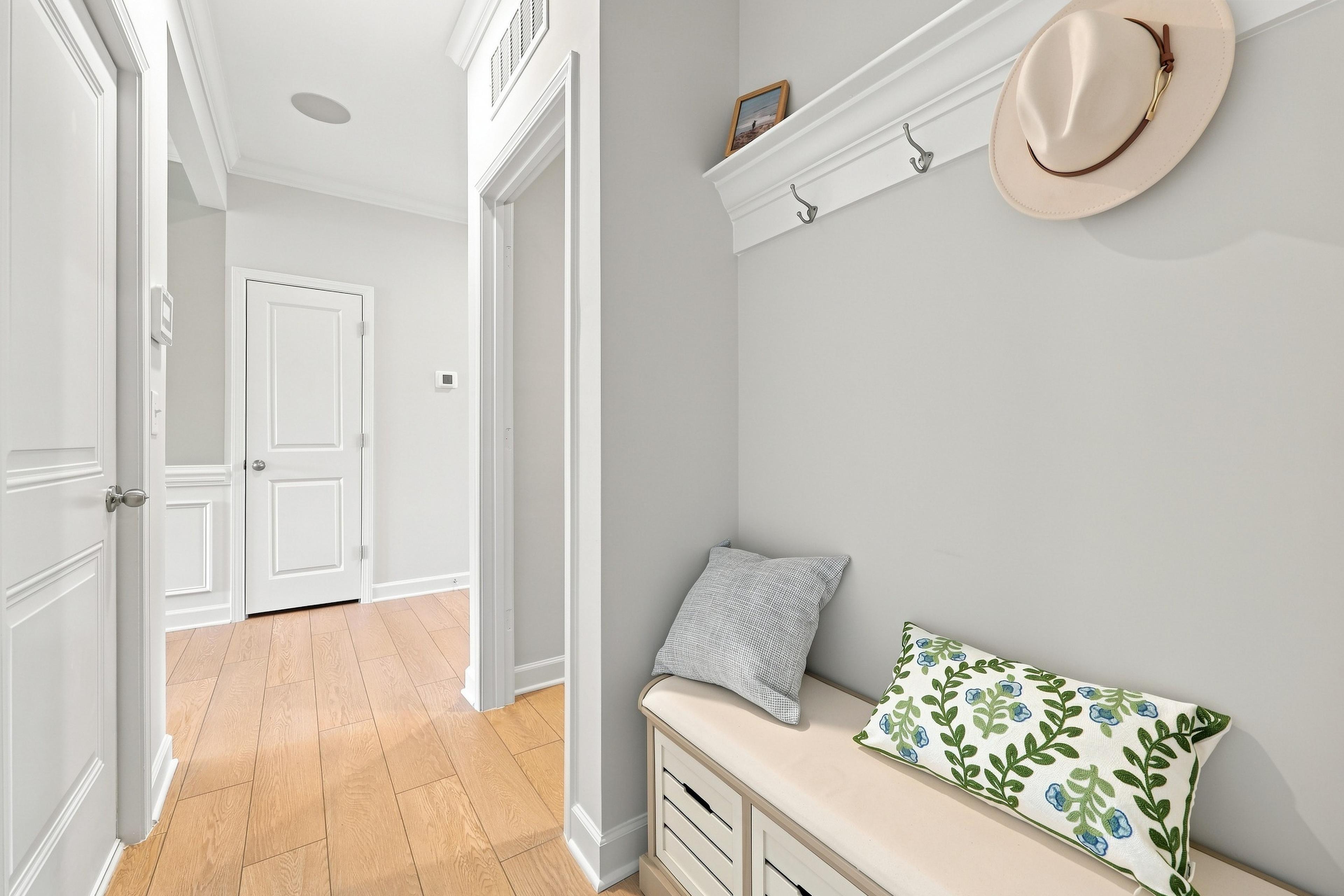 Mudroom bench with storage and wall hooks in The Daphne floor plan featuring light wood flooring and neutral decor.