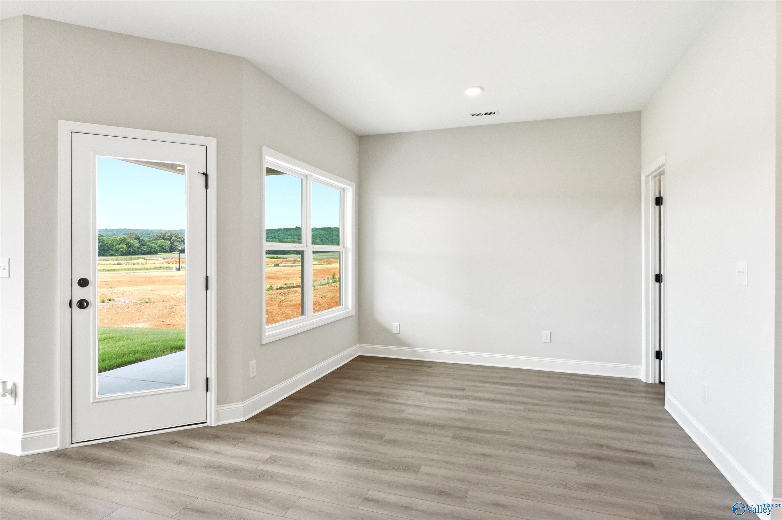 Bright living area with wood-look flooring and backyard view in The Daphne F floor plan at Berry Cove, New Market, AL.