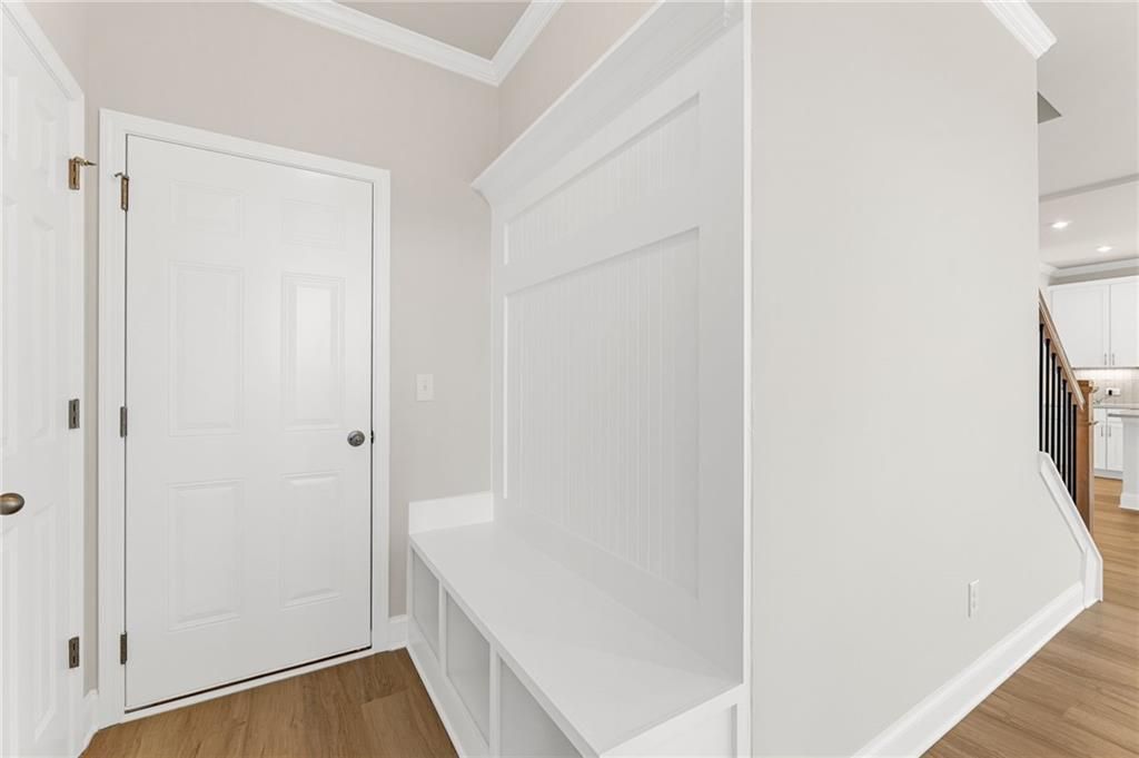 Built-in white mudroom bench with open cubbies and hardwood floors in Davidson Homes The Willow B, Hoschton, Georgia