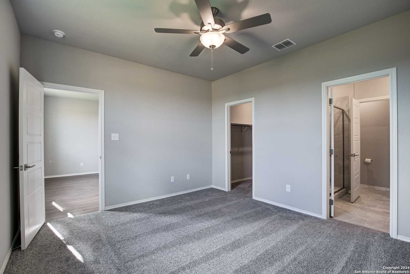 Spacious master bedroom with ceiling fan, walk-in closet, and en-suite bath in Davidson Homes The Frio B, San Antonio, Texas