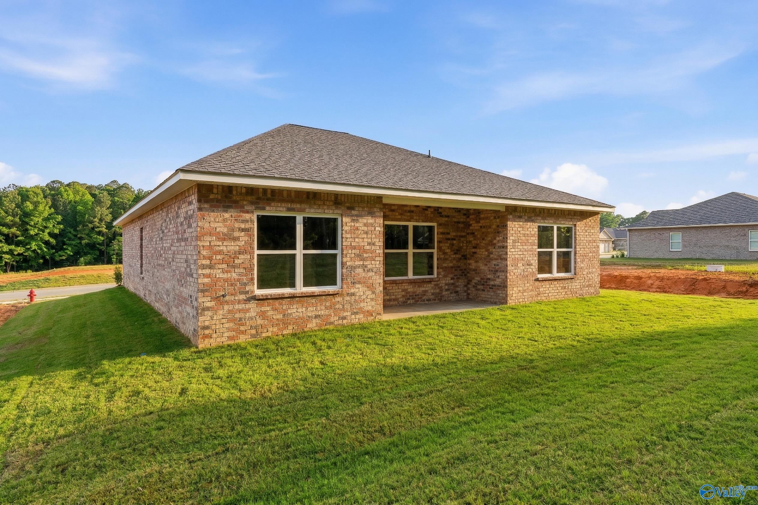 Brick single-story home with gabled roof and large windows on green lawn in The Highlands, Arab, Alabama
