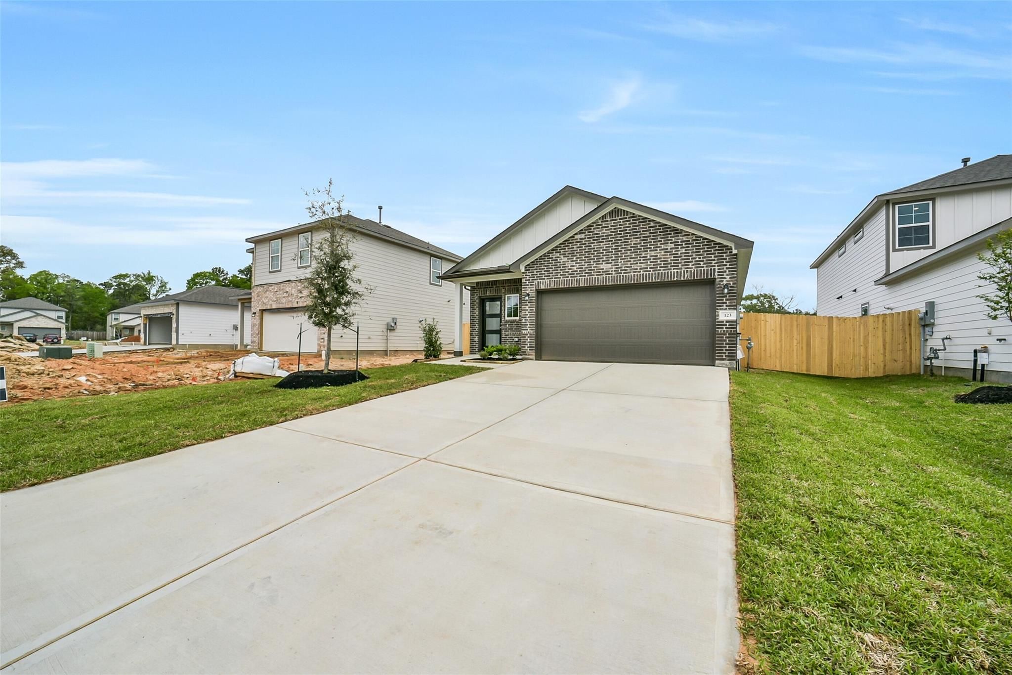 Modern brick 1-story home with 2-car garage, driveway, and landscaped yard in Caney Creek Place, Conroe, Texas by Davidson Homes The Frio F