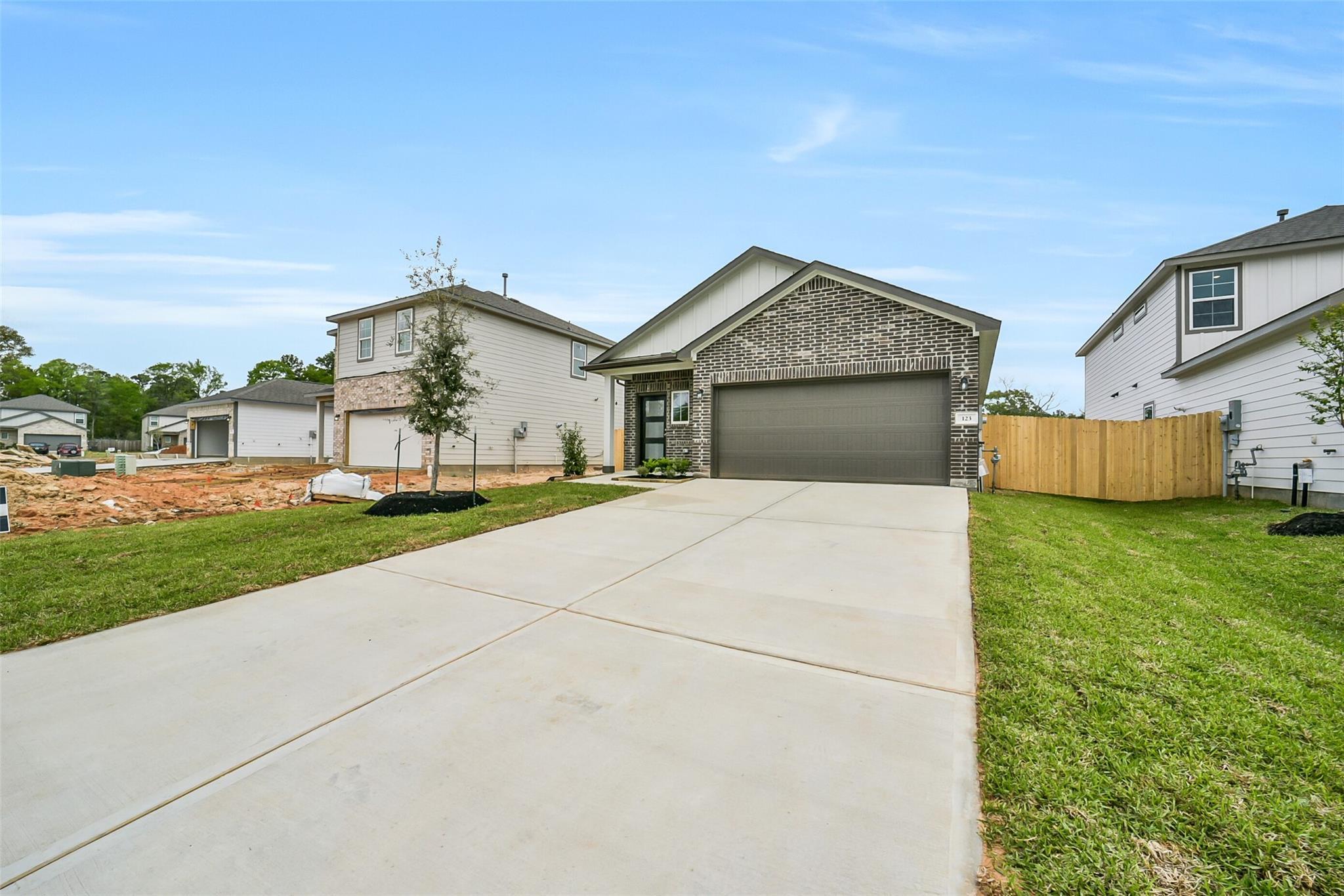 Modern brick 1-story home with 2-car garage, driveway, and landscaped yard in Caney Creek Place, Conroe, Texas by Davidson Homes The Frio F