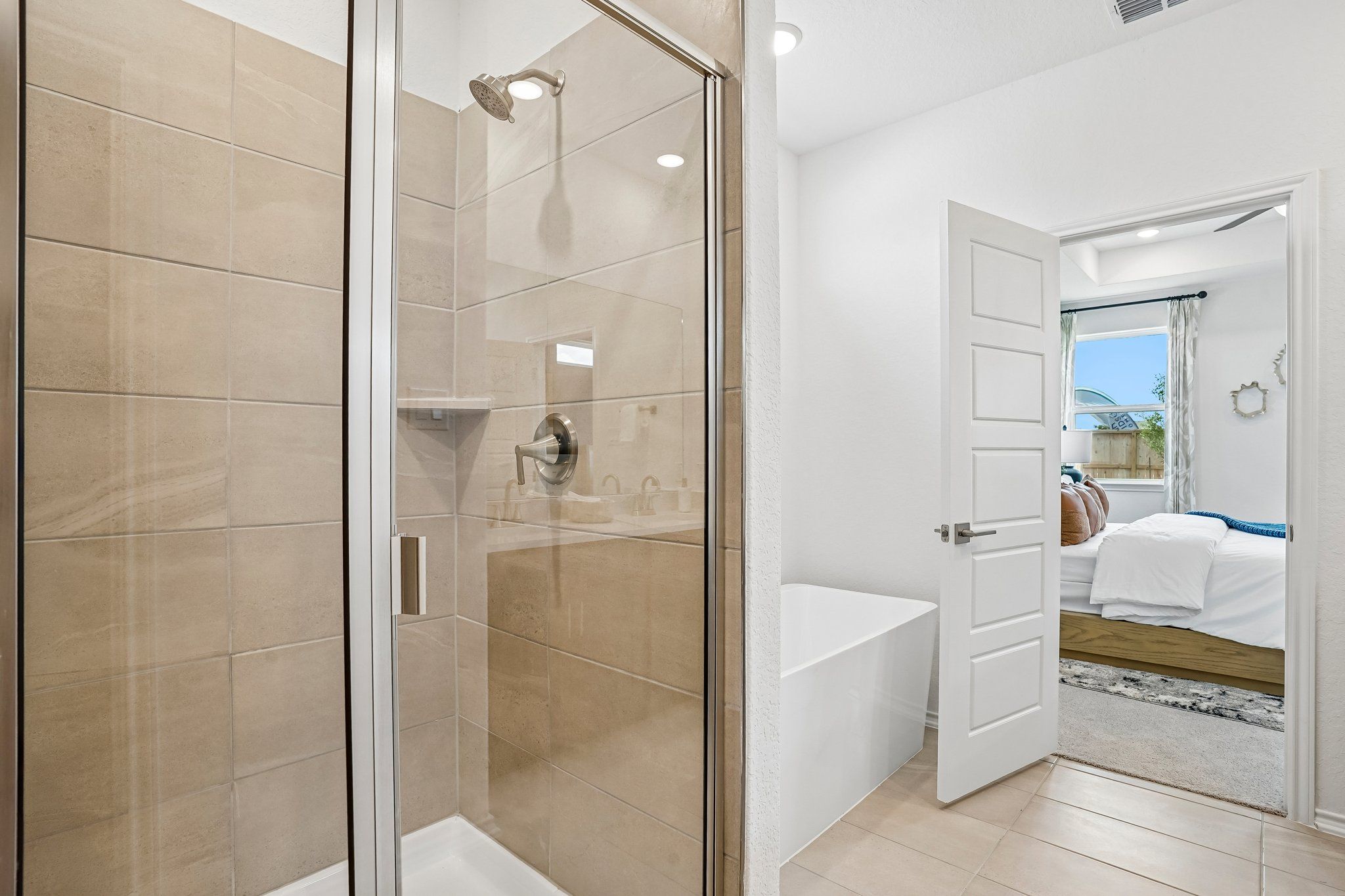Modern bathroom with a glass-enclosed tile shower and soaking tub at Morgan Meadows in San Antonio by Davidson Homes.