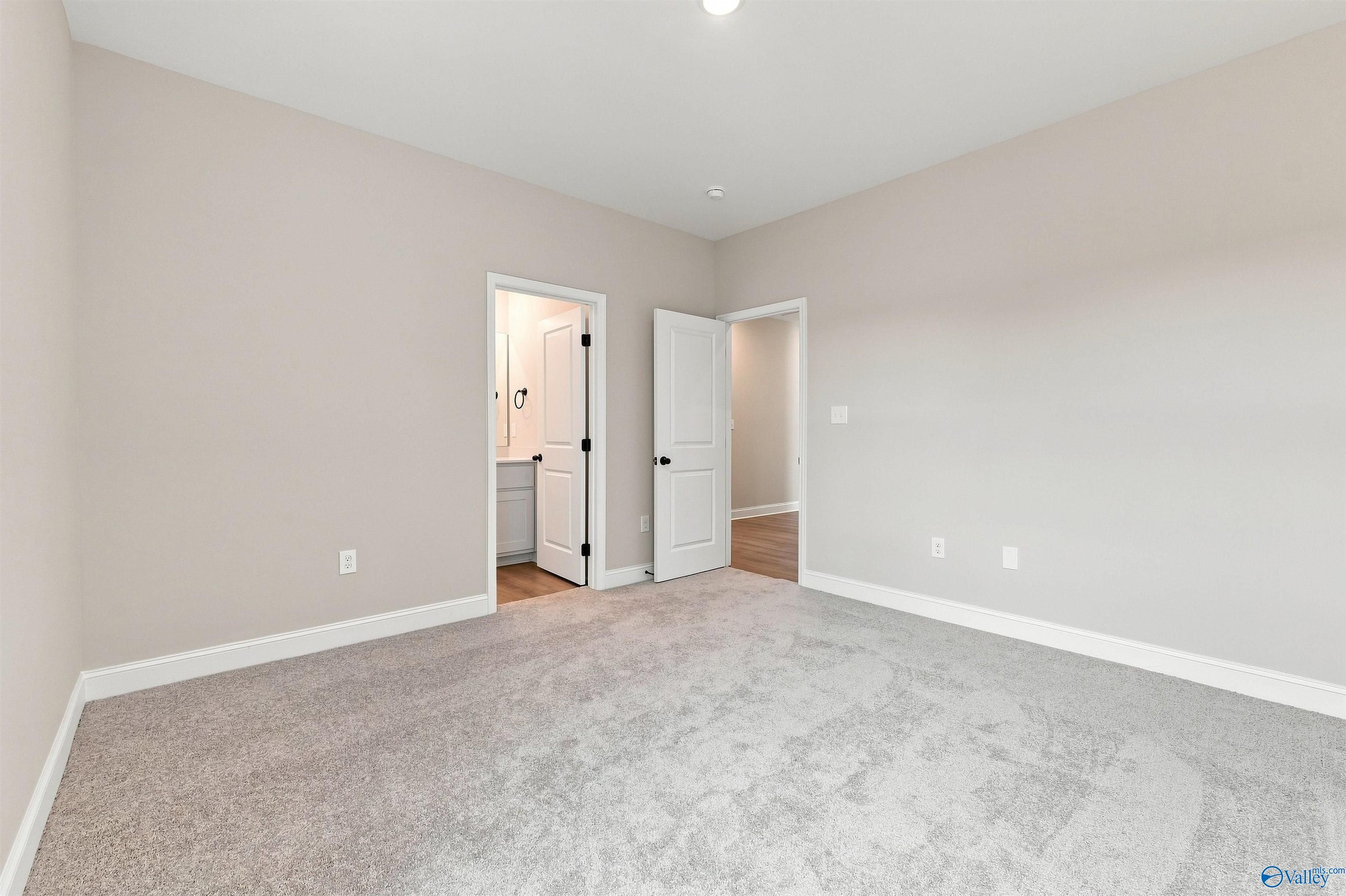 Spacious bedroom with plush carpet and ensuite bathroom in The Oxford floor plan at Kendall Farms, Toney, Alabama.