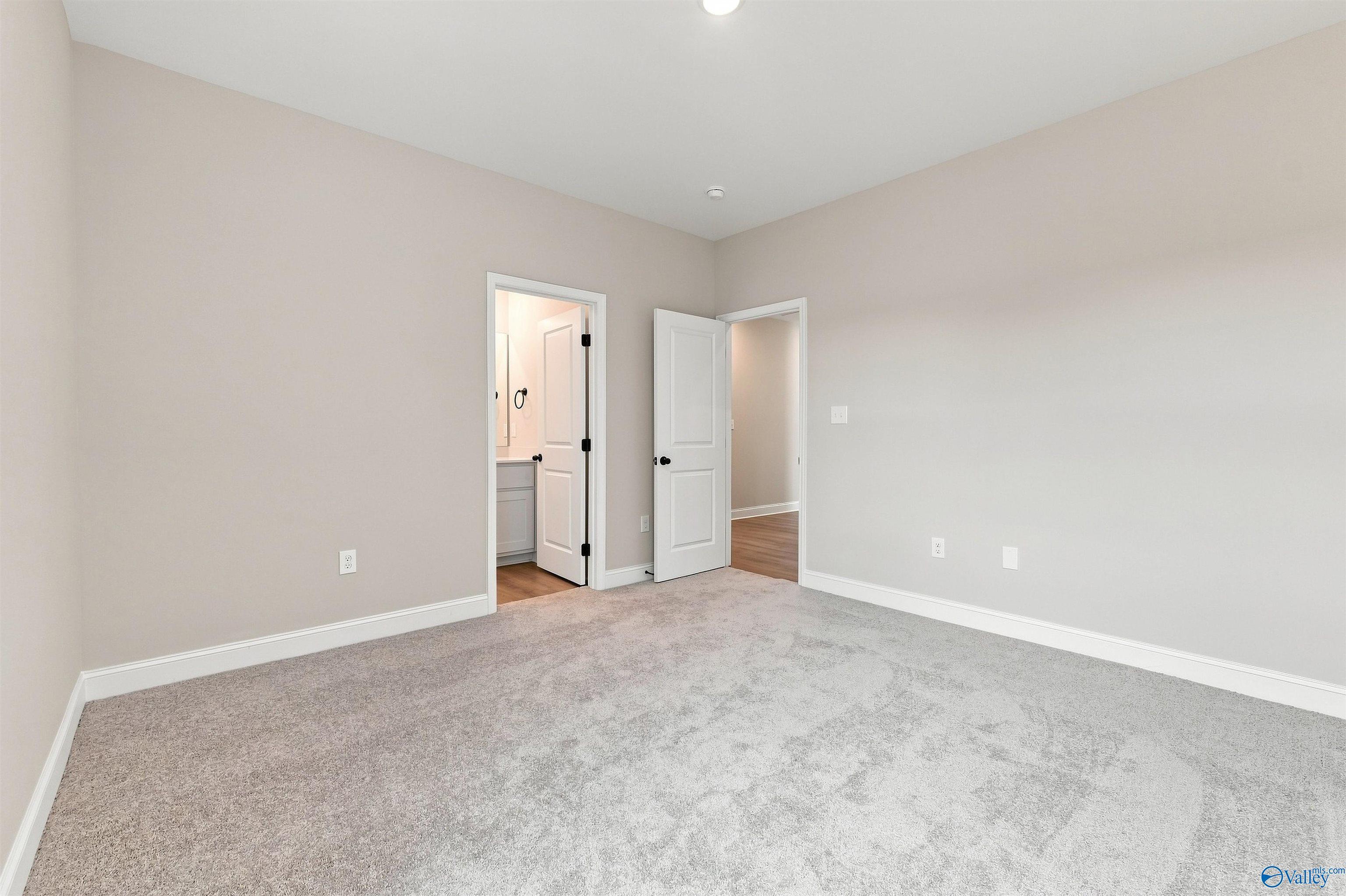 Spacious bedroom with plush carpet and ensuite bathroom in The Oxford floor plan at Kendall Farms, Toney, Alabama.