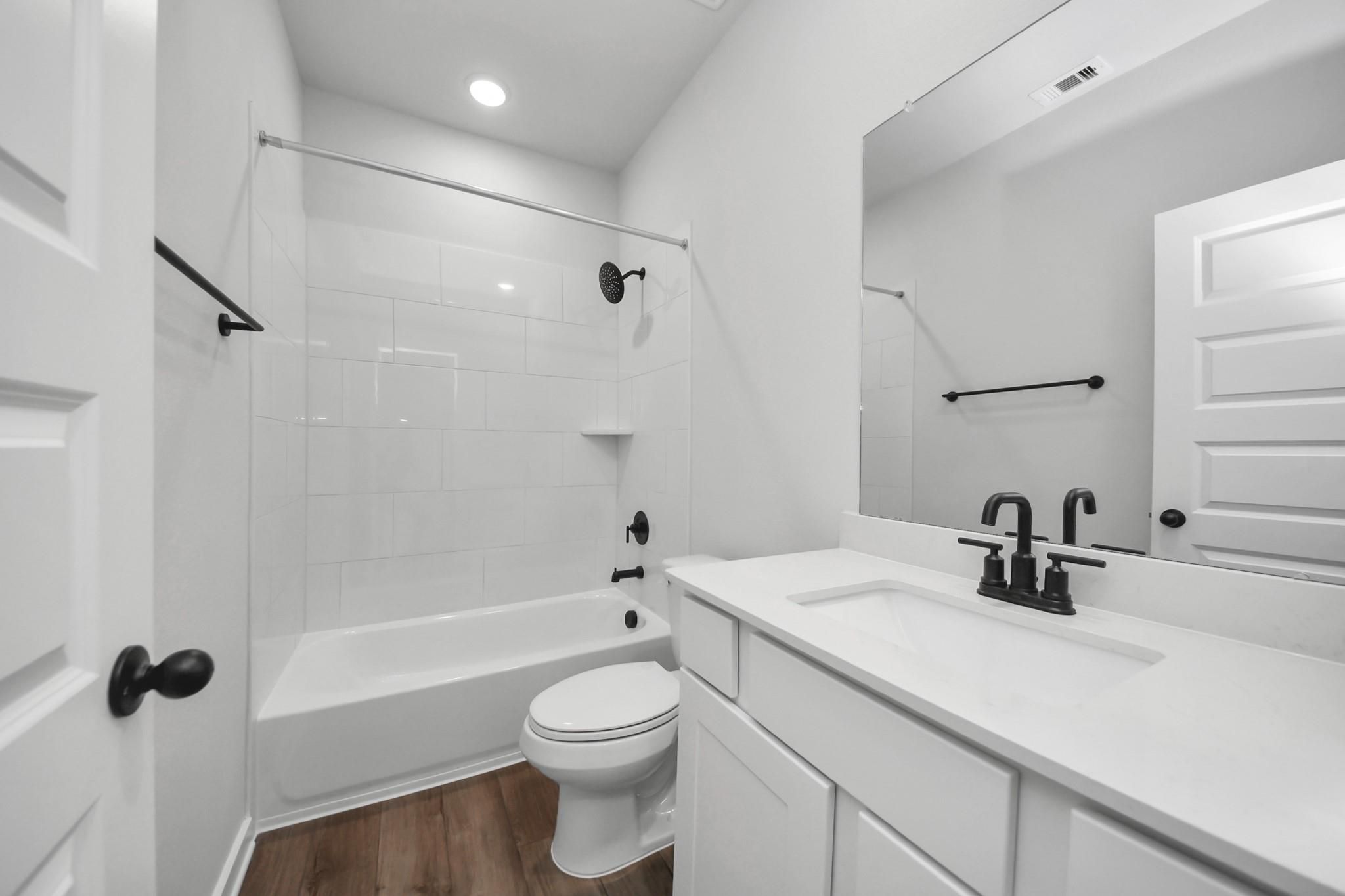 Modern bathroom with white vanity, tile shower surround, and black fixtures in The Riviera C home at River Ranch Meadows.