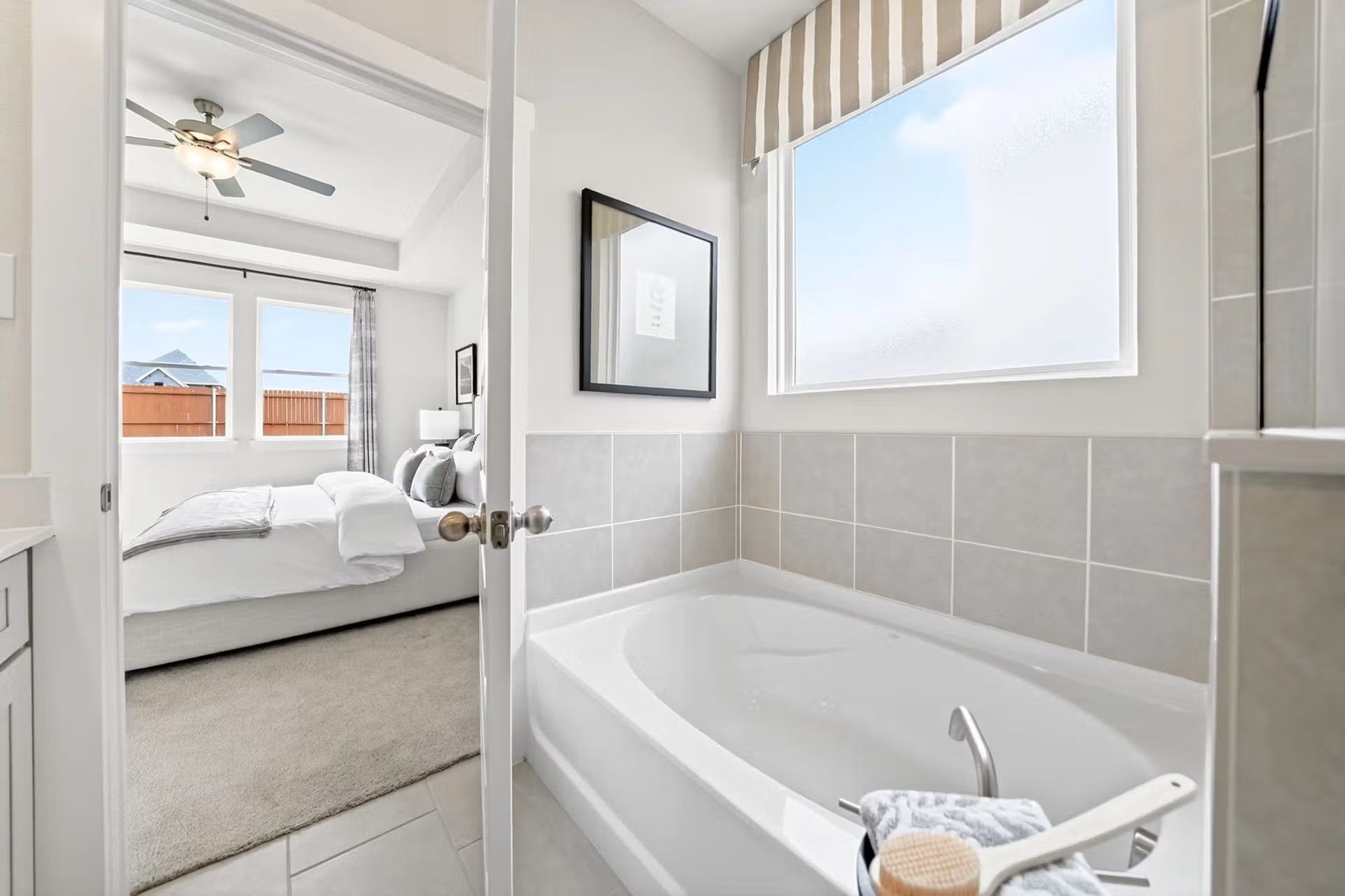 Modern master bathroom with soaking tub leading into a spacious bedroom in a Davidson Homes Laurel I floor plan in Heartland.