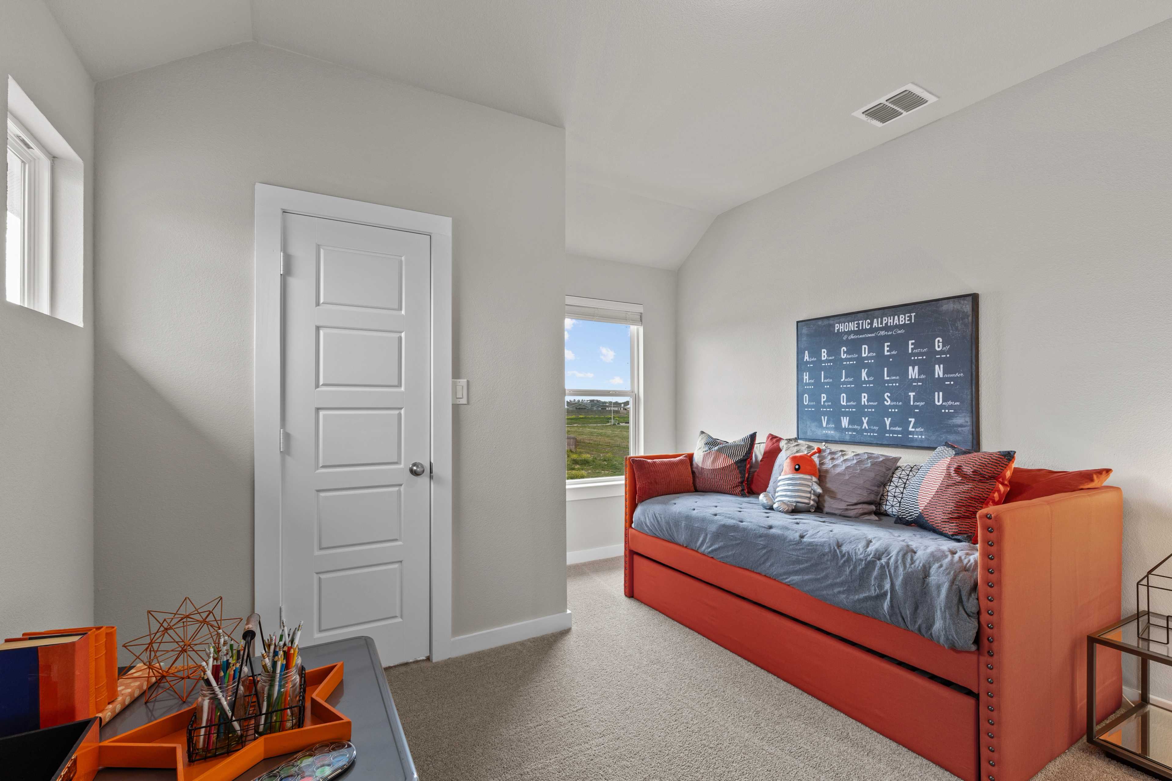 Cozy study nook at Hannah Heights in Seguin Texas with red tufted daybed, art supplies desk, and scenic field view