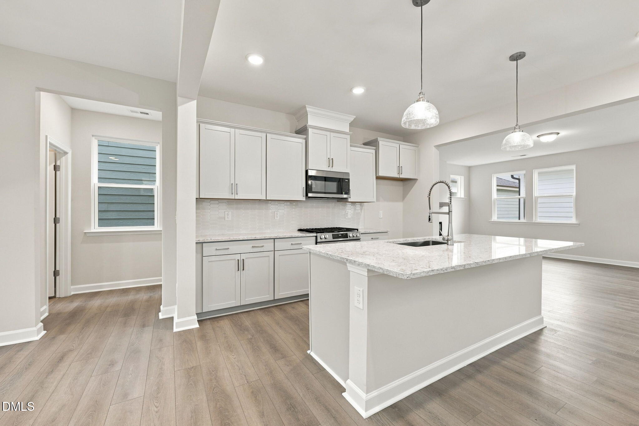 White shaker kitchen with granite island, pendant lights, and stainless appliances in Davidson Homes The Alexander B, Knightdale NC