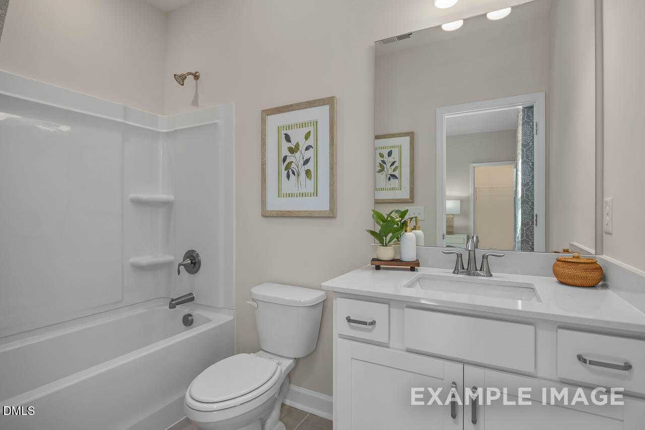 Bright bathroom with white soaking tub, glass shower, and modern vanity in Davidson Homes Hickory II C, Wake Forest, NC