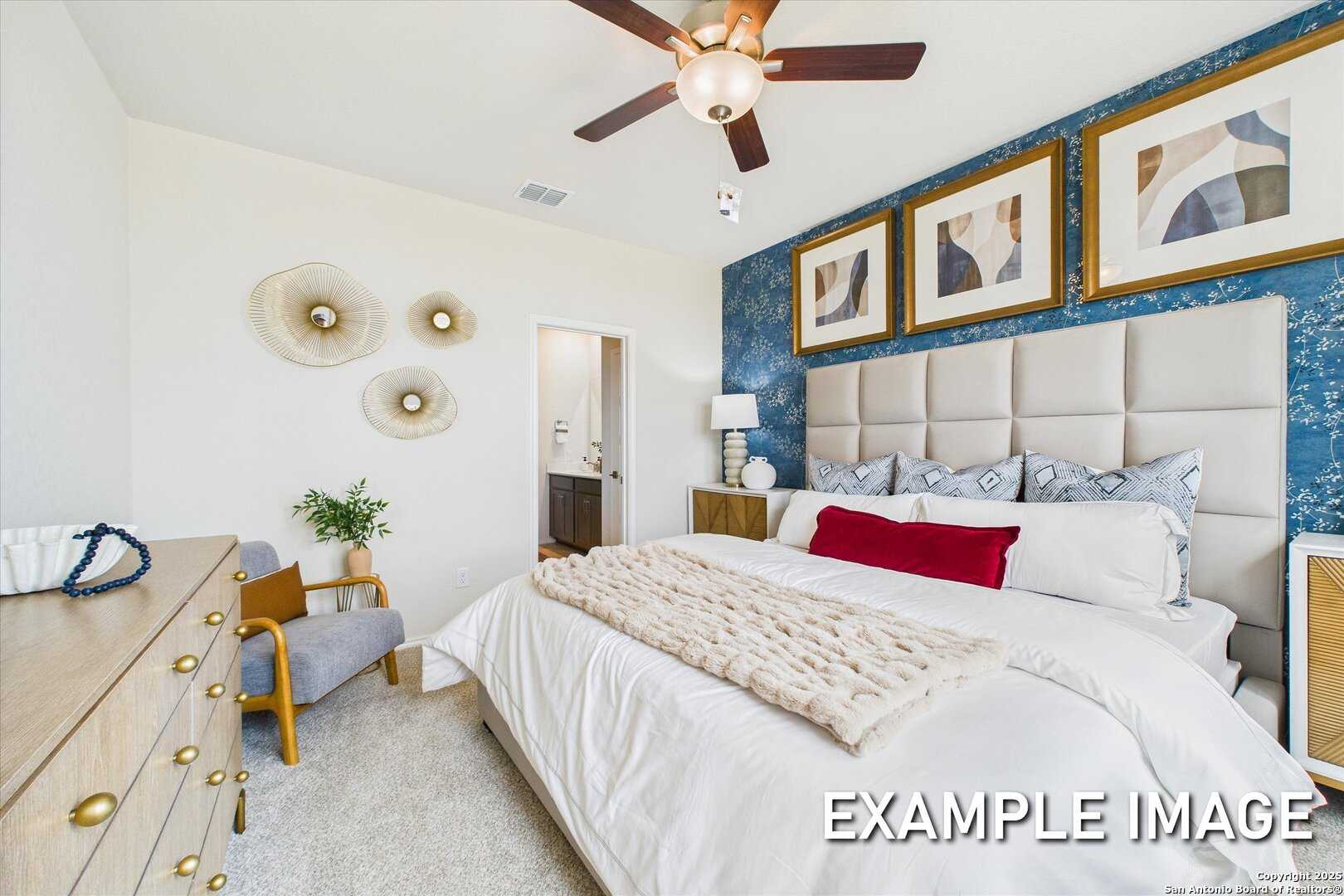 Elegant master bedroom with tufted beige headboard, ceiling fan, abstract wall art in Davidson Homes The Brazos C, San Antonio