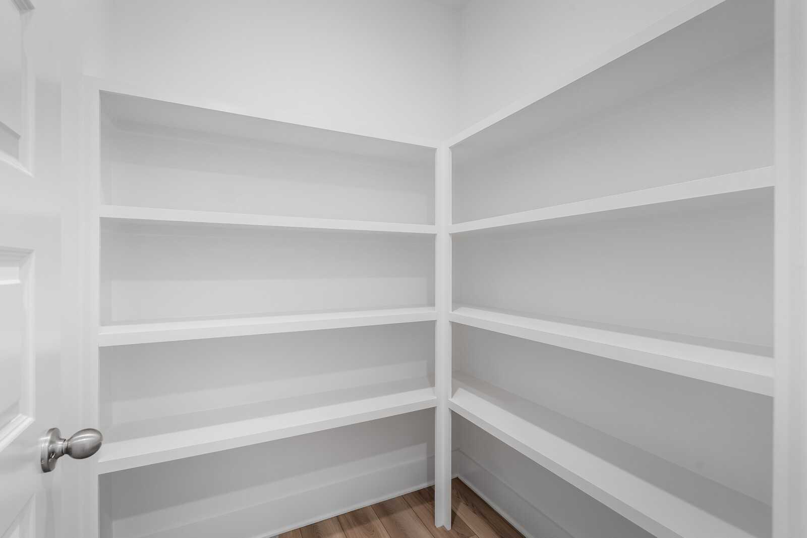 Spacious corner walk-in pantry with white tiered shelving in Davidson Homes The Hathaway, Murfreesboro, TN