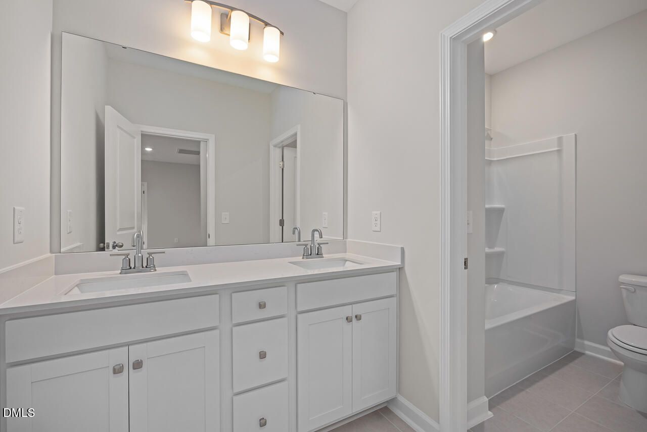 Modern bathroom with double vanity and tub-shower combo in The Ashport G floor plan at Sage on North Main, Wake Forest.
