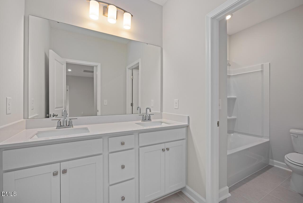 Modern bathroom with double vanity and tub-shower combo in The Ashport G floor plan at Sage on North Main, Wake Forest.