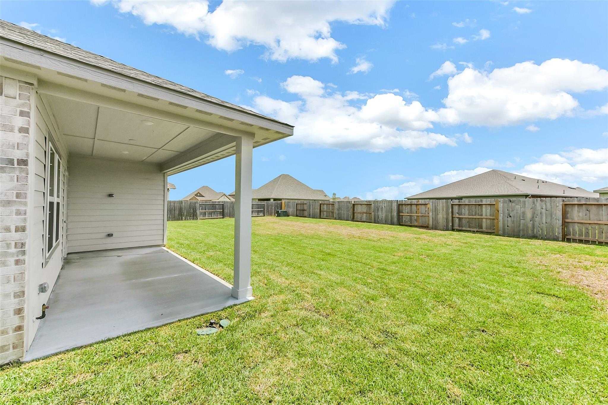 Covered back patio with privacy fence and lush green backyard in Davidson Homes The Laguna C, Sierra Vista, Rosharon, Texas