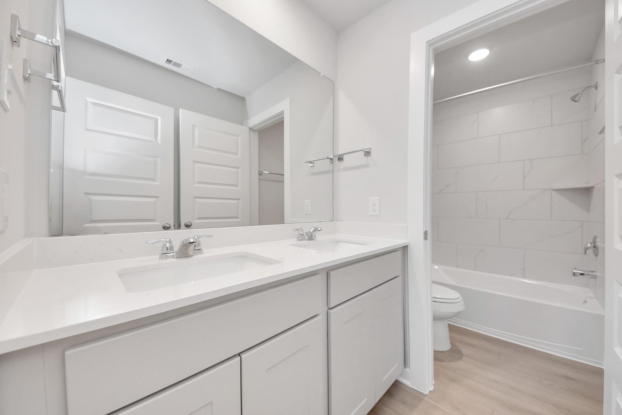 Modern bathroom with dual vanity and tub-shower combo in The Blanco F floor plan at Spring Branch Crossing, Conroe, Texas.