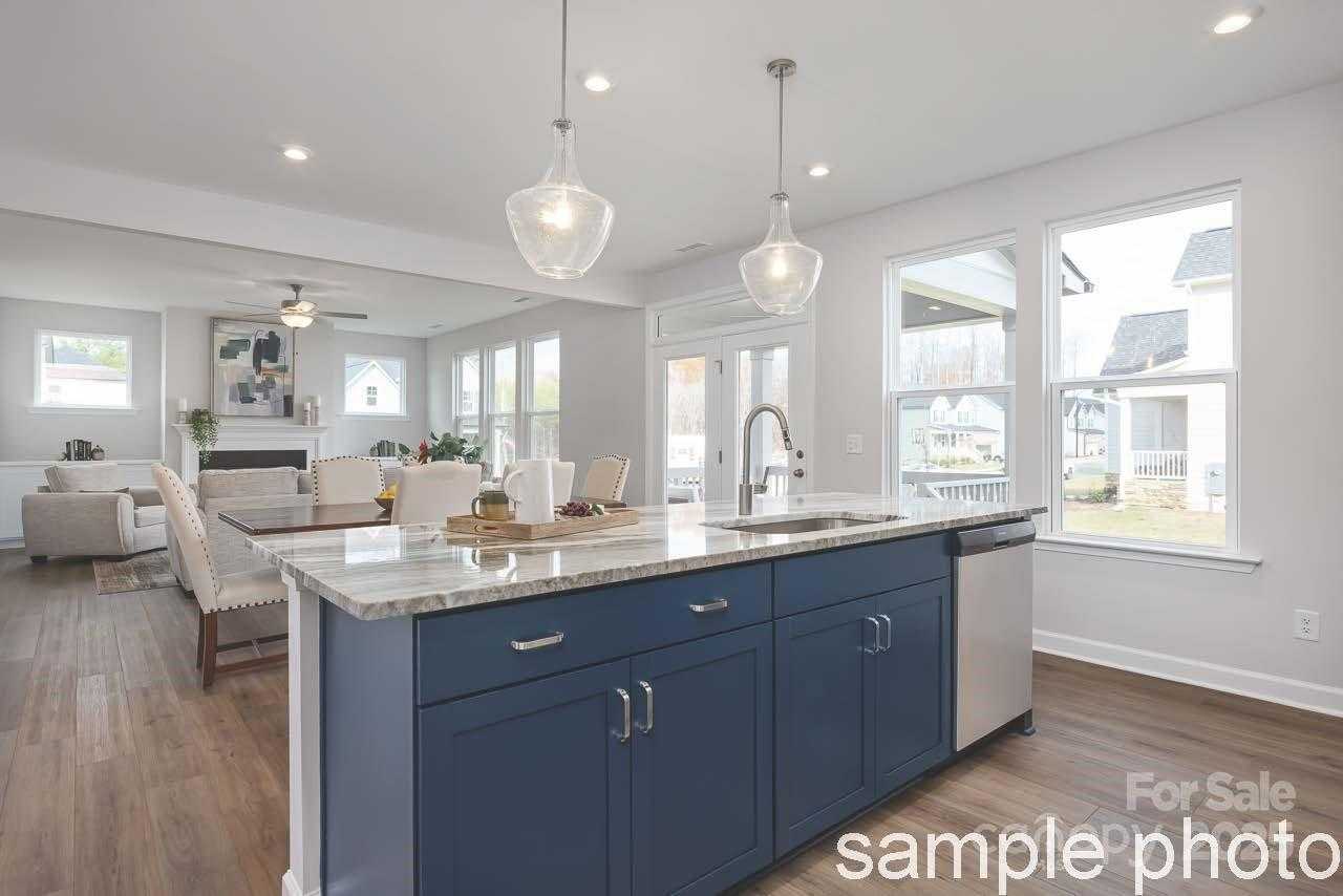 Open-concept kitchen with navy blue island, granite counters, and stainless sink in Davidson Homes The Chestnut F, Belmont NC