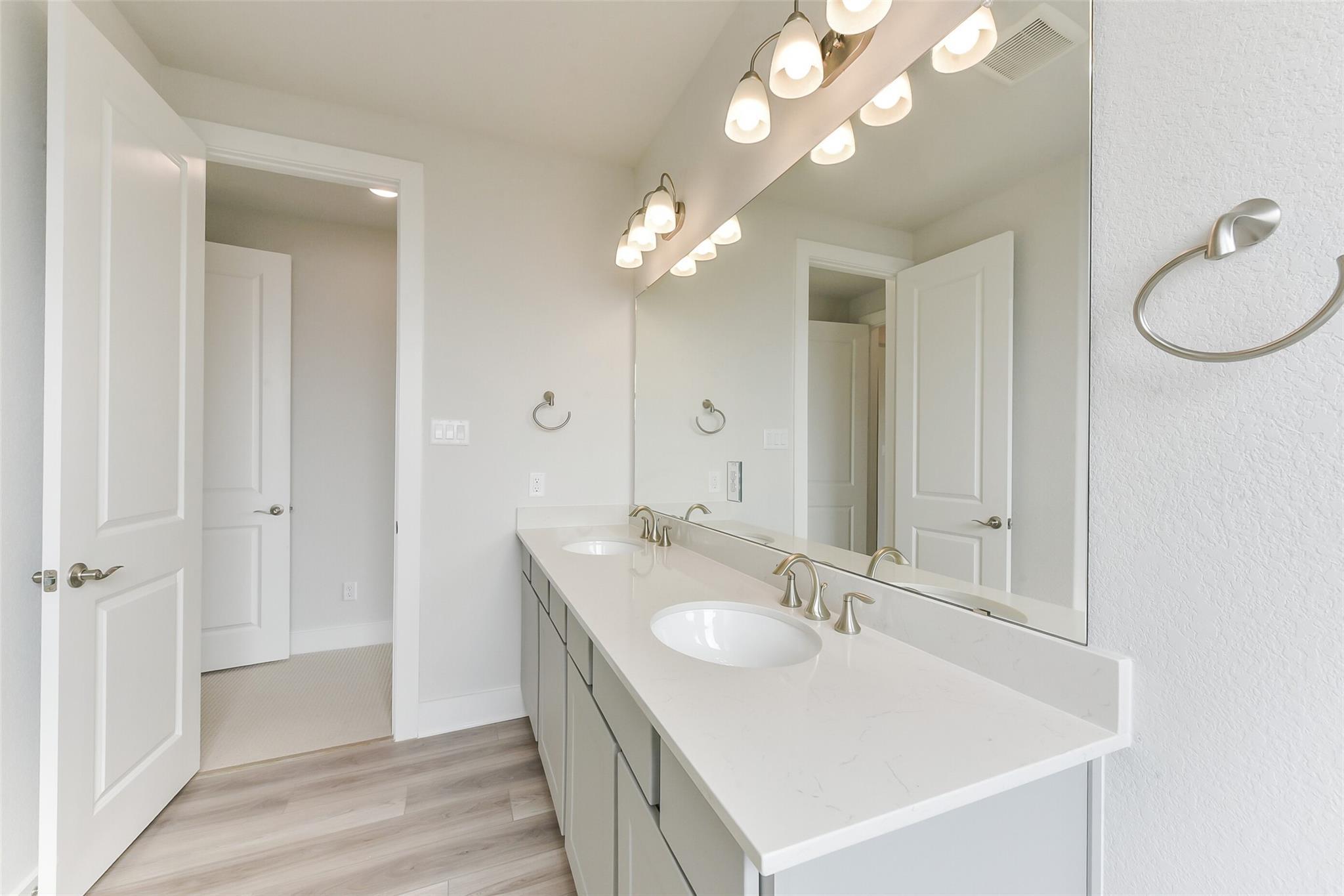 Modern master bathroom double vanity with quartz countertop, chrome faucets, and large mirror in Davidson Homes The Edward A, Lago Mar, Texas City