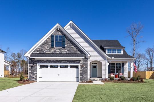 Modern craftsman home exterior in Prince Place Fuquay-Varina NC by Davidson Homes featuring stone garage and covered front porch