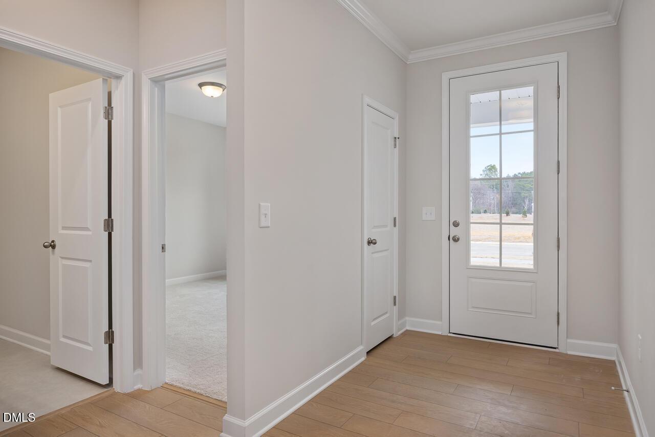 Bright entry foyer with hardwood floors, white doors, and glass-paneled front door in The Daphne C 3-bedroom home, Lillington, NC