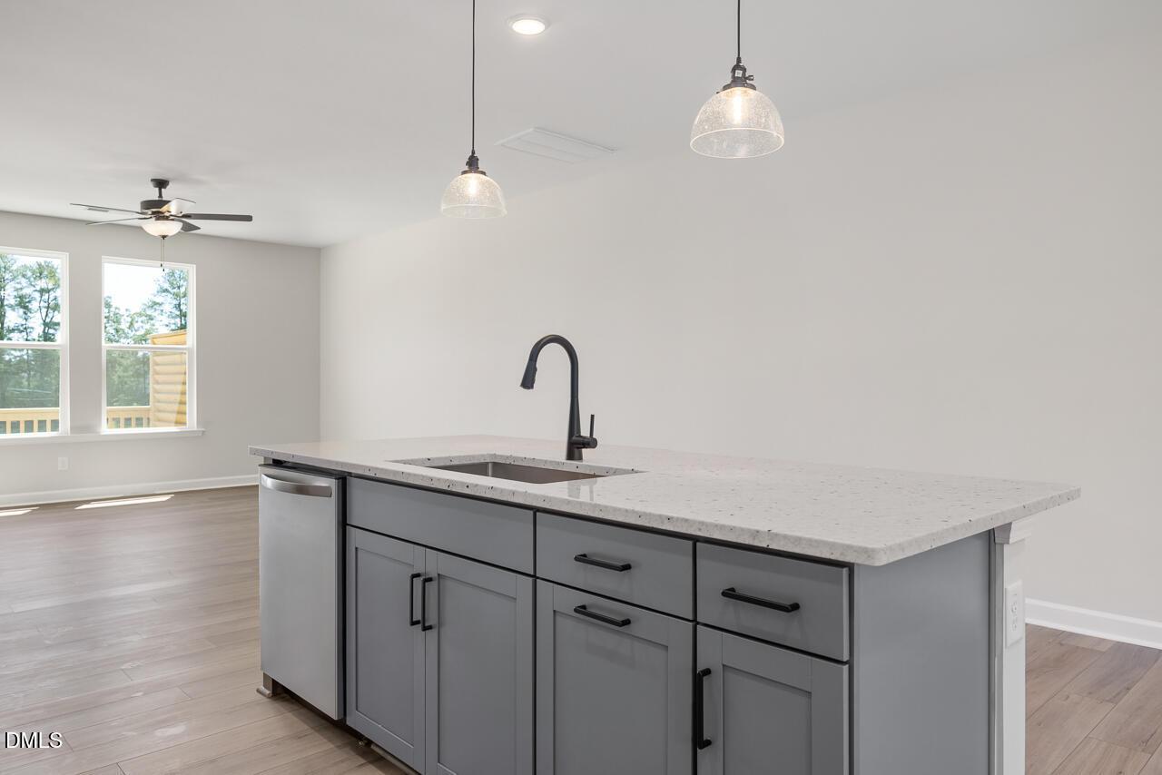 Modern kitchen island with quartz countertops and pendant lighting in The Mitchell floor plan at Camden Park, Knightdale.