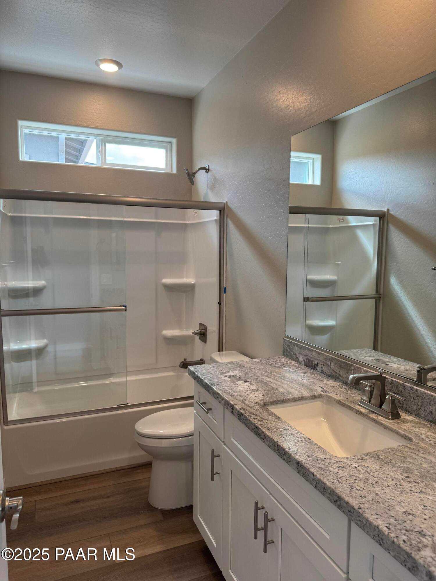 Modern bathroom with frameless glass shower, deep soaking tub, quartz vanity, and wood flooring in Davidson Homes The Monarch A, Prescott, Arizona