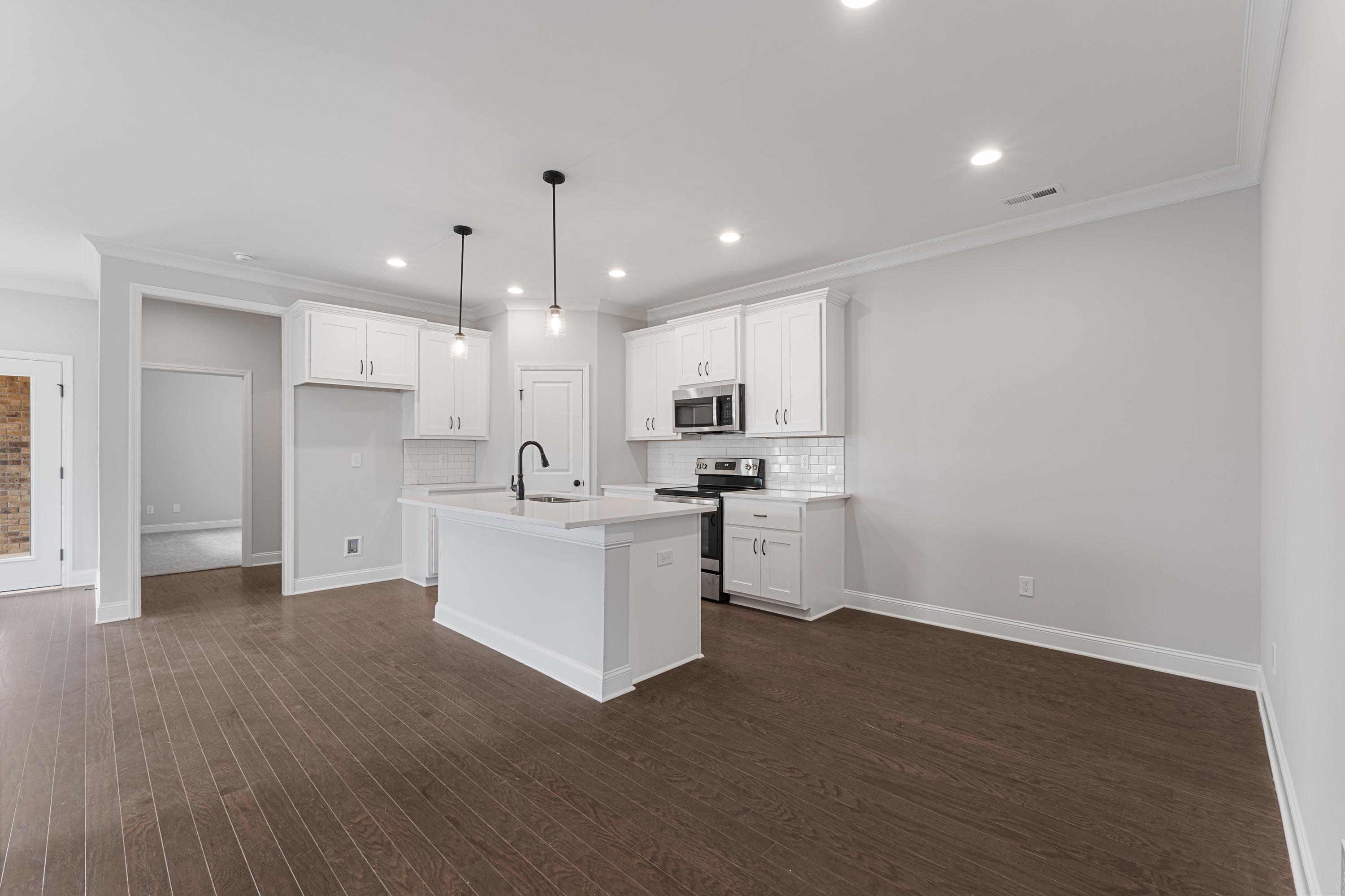 Modern kitchen in The Copeland Davidson Homes design with white shaker cabinets, large island, stainless appliances, and hardwood floors