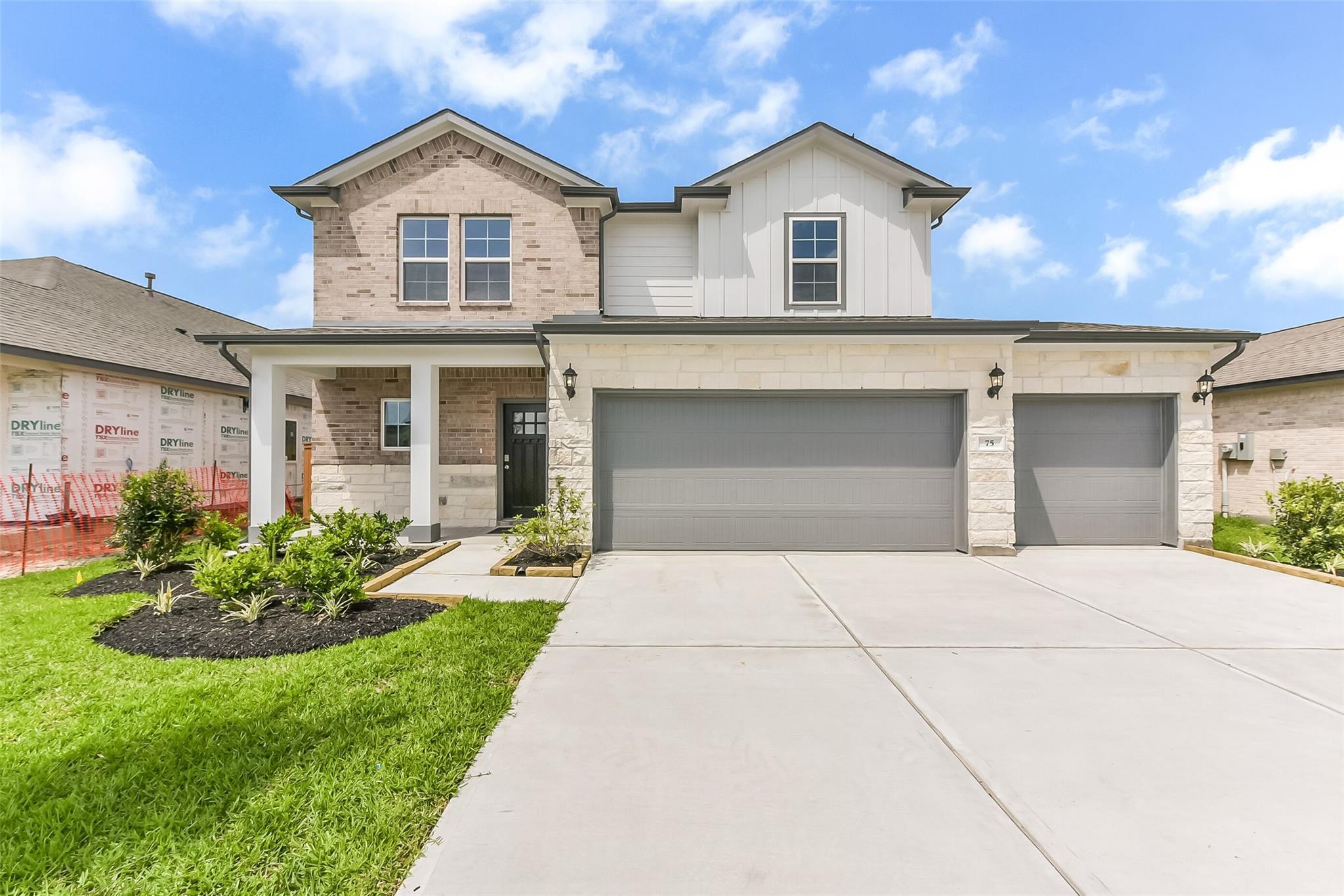 Modern two-story brick and white home with 3-car garage, covered porch, and landscaped yard in River Ranch Meadows, Dayton, Texas