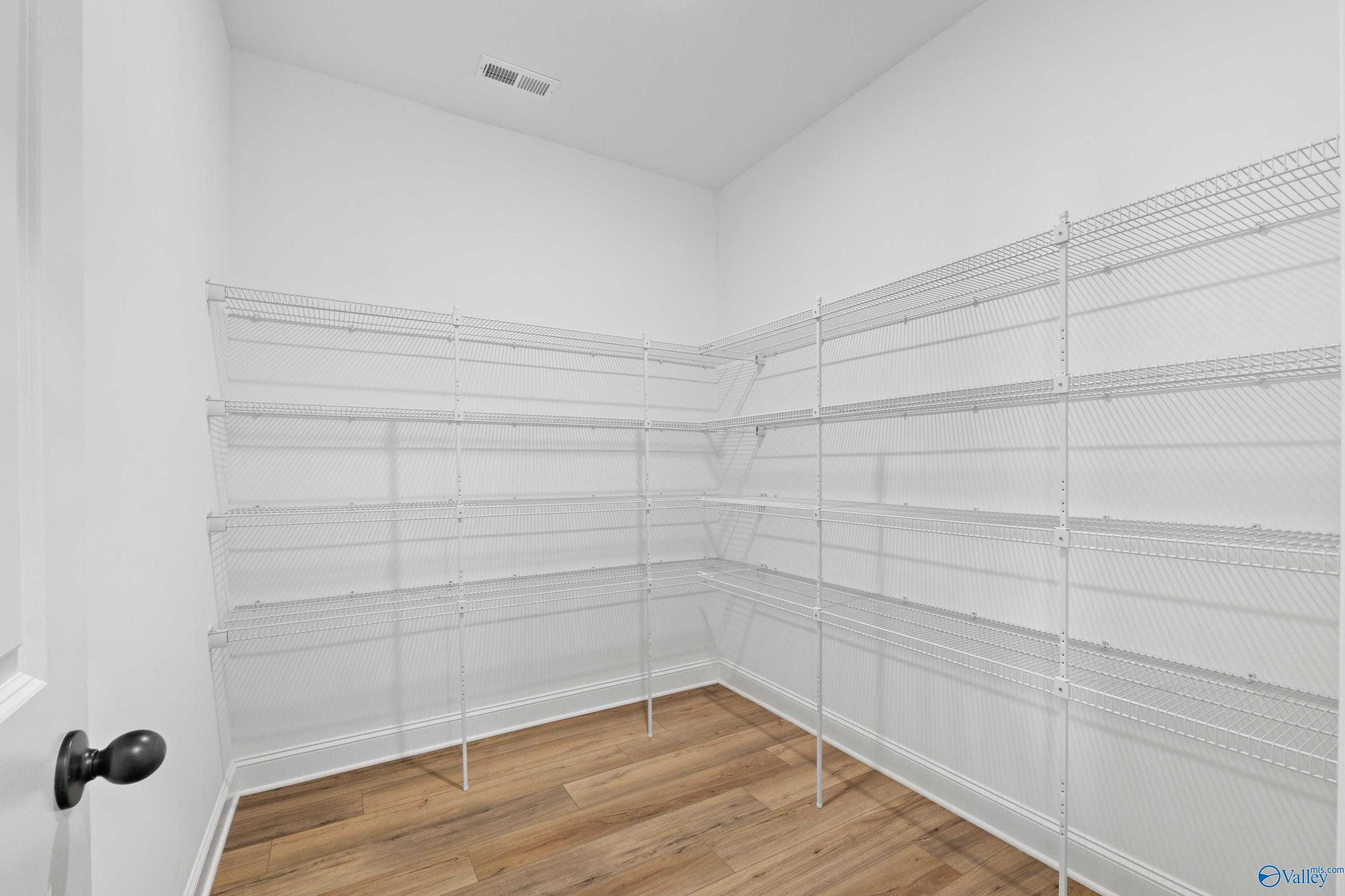 Spacious walk-in pantry with white wire shelving and hardwood floors in Davidson Homes The Valencia, Meridianville, Alabama