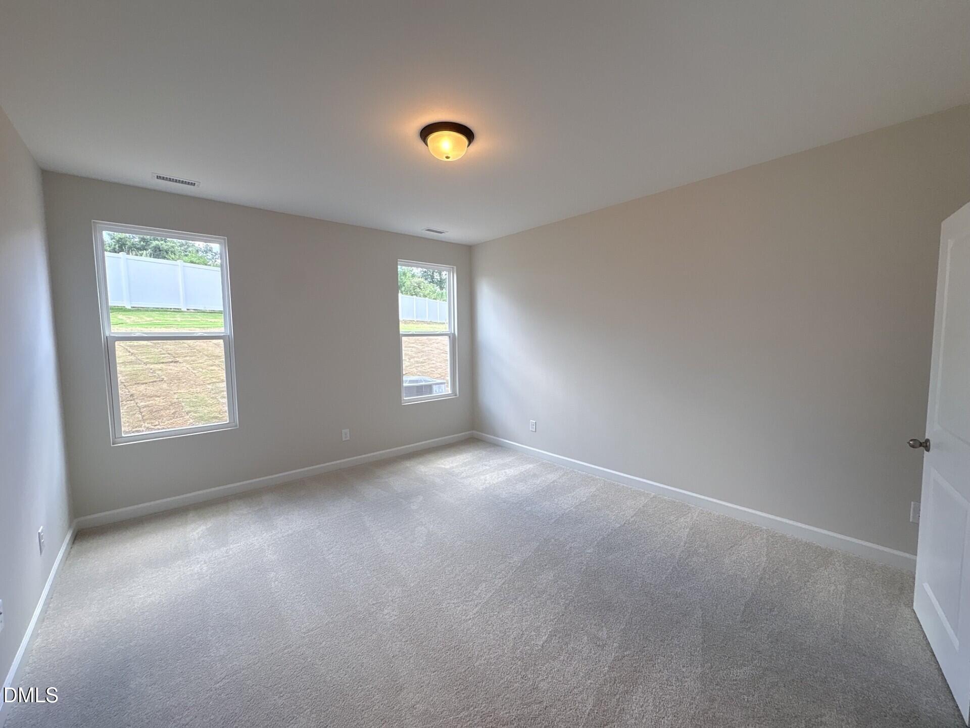 Spacious carpeted bedroom with neutral walls in The Ash C floor plan at Woodland Crossing, Zebulon, North Carolina.