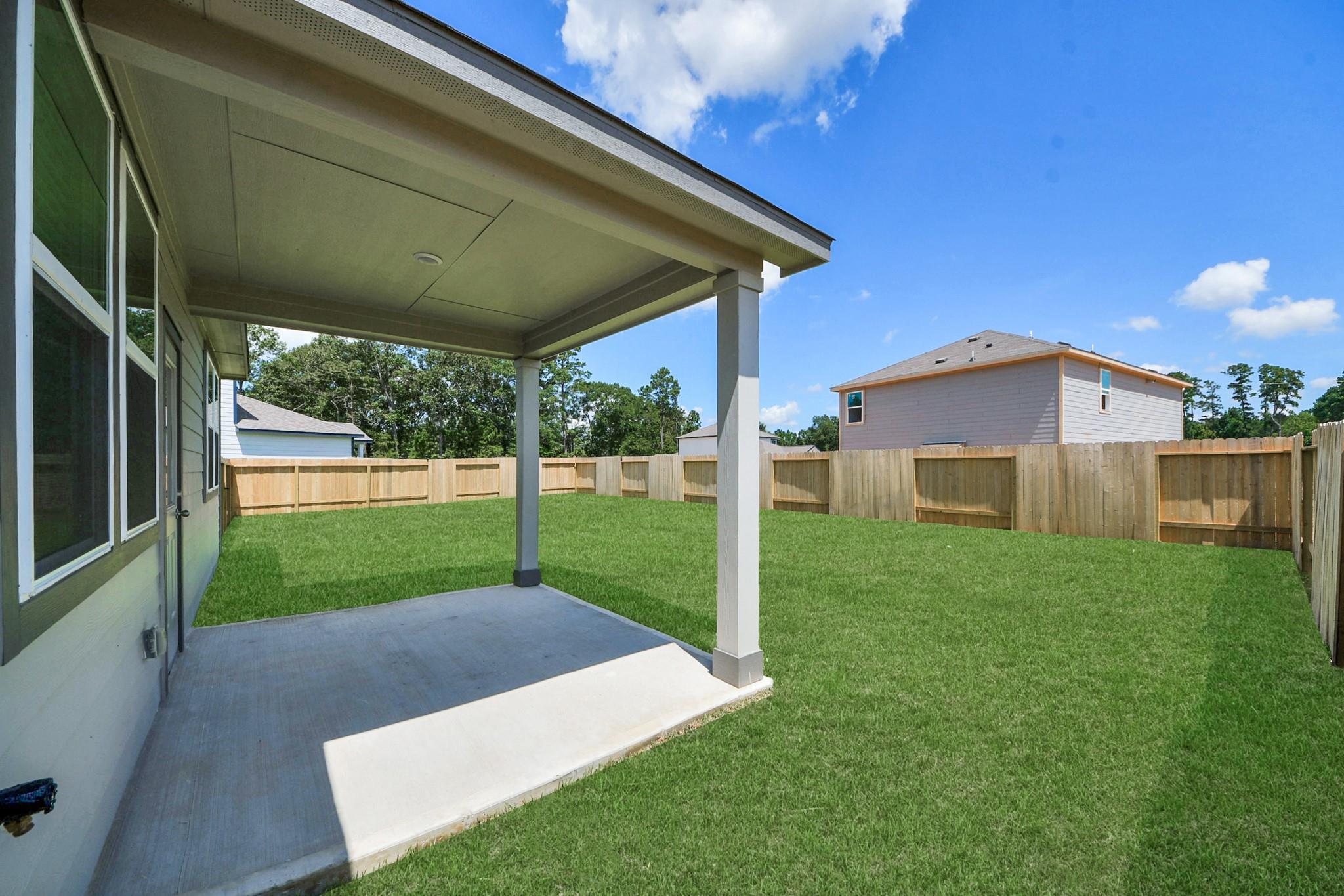 Covered back patio and spacious fenced backyard at The Brazos F floor plan in Liberty Estates, Cleveland, Texas.