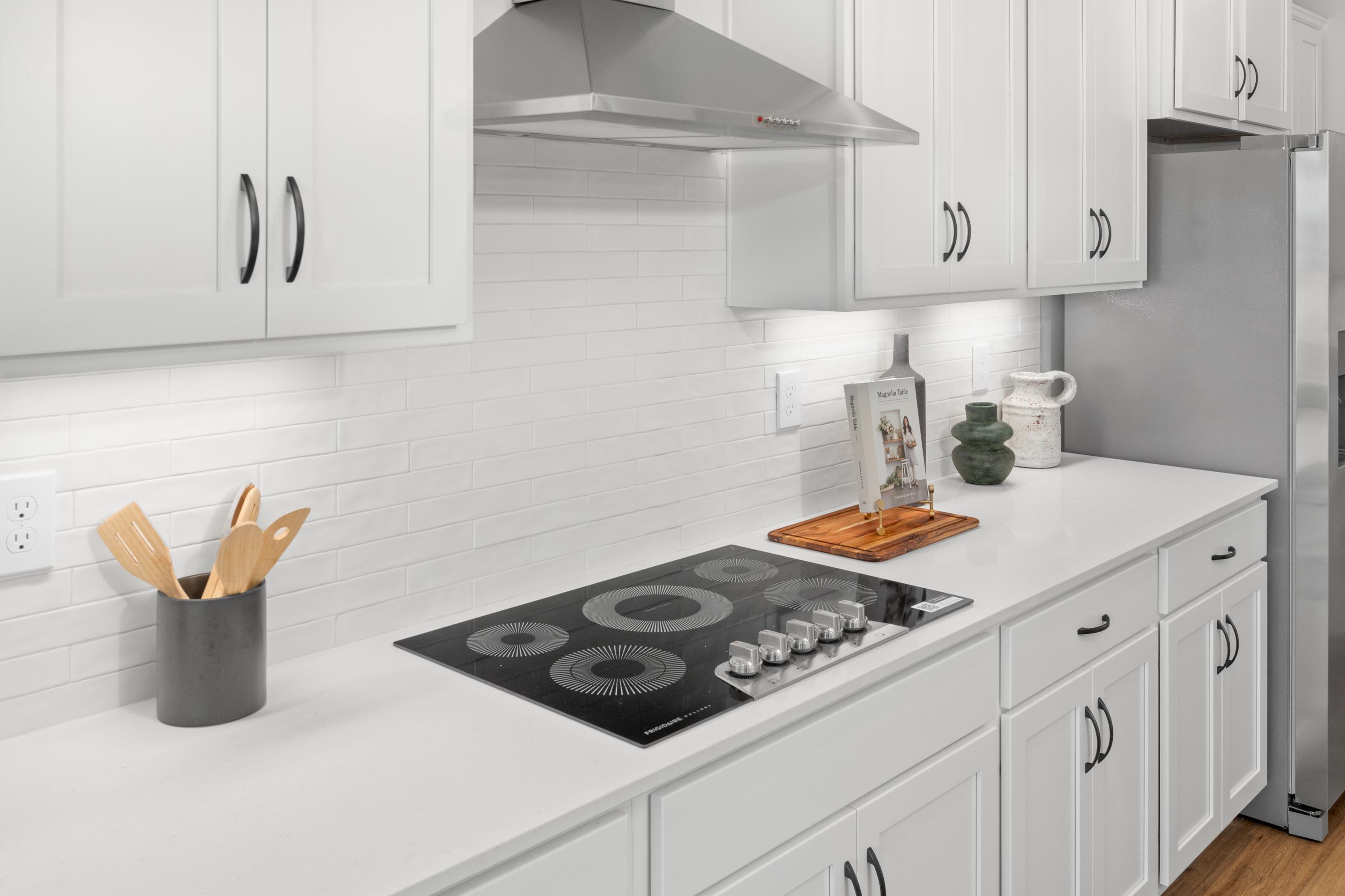 Spacious white kitchen in Briercreek Meridianville AL with induction cooktop subway tile backsplash stainless hood