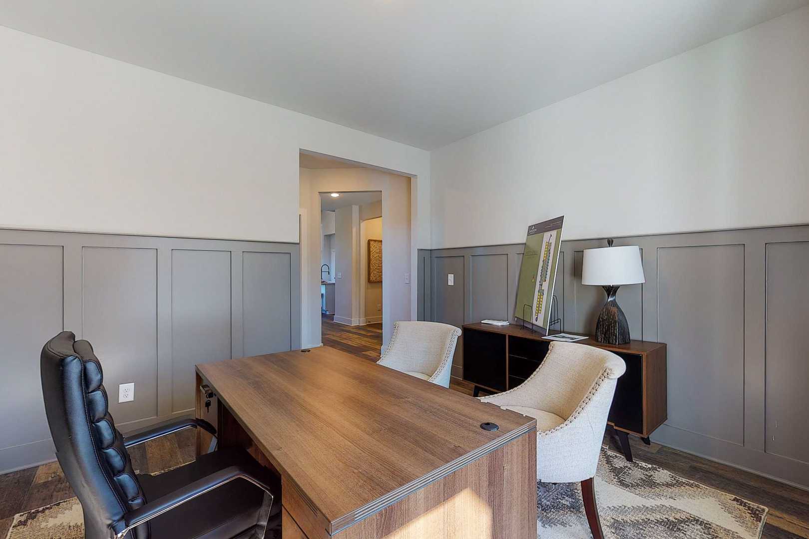 Modern home office at Liberty Creek in Gallatin TN with wooden executive desk, leather chair, gray wainscoting, and lamps