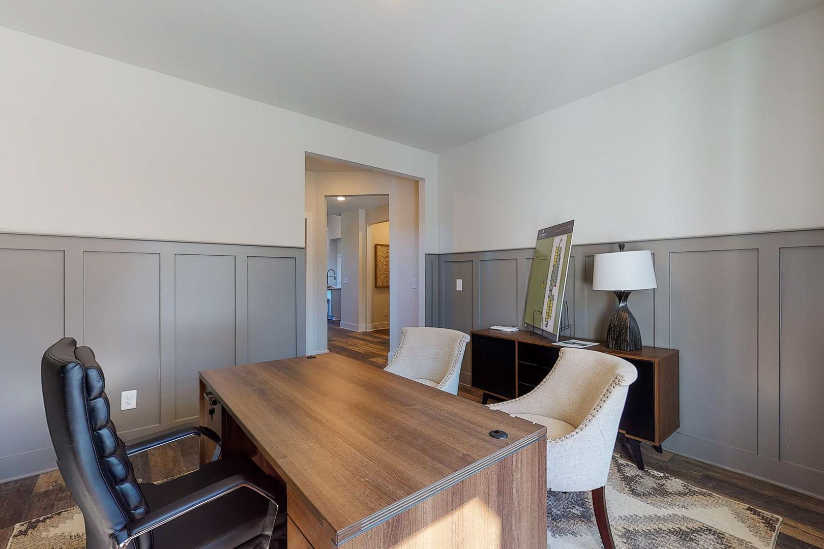 Modern home office at Liberty Creek in Gallatin TN with wooden executive desk, leather chair, gray wainscoting, and lamps