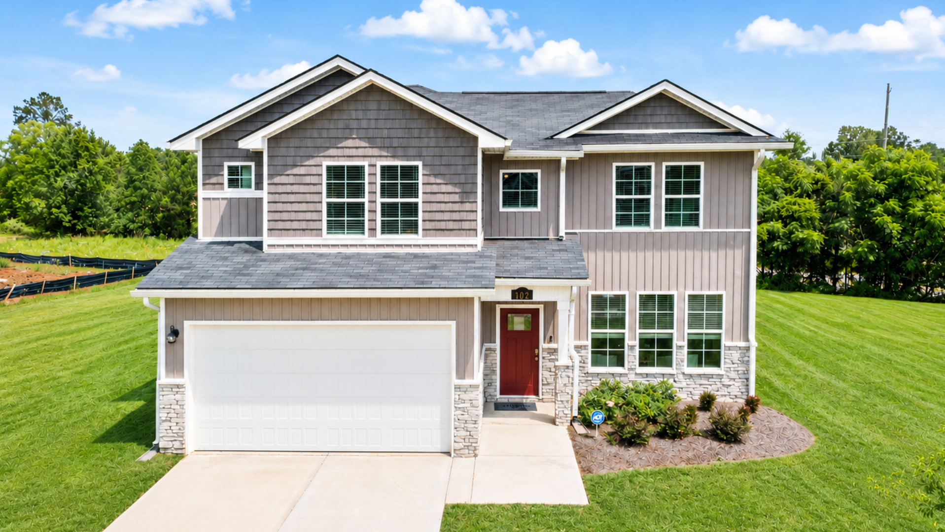 Two-story Davidson Homes model house with red door, stone accents, and two-car garage in a Central Georgia residential area.