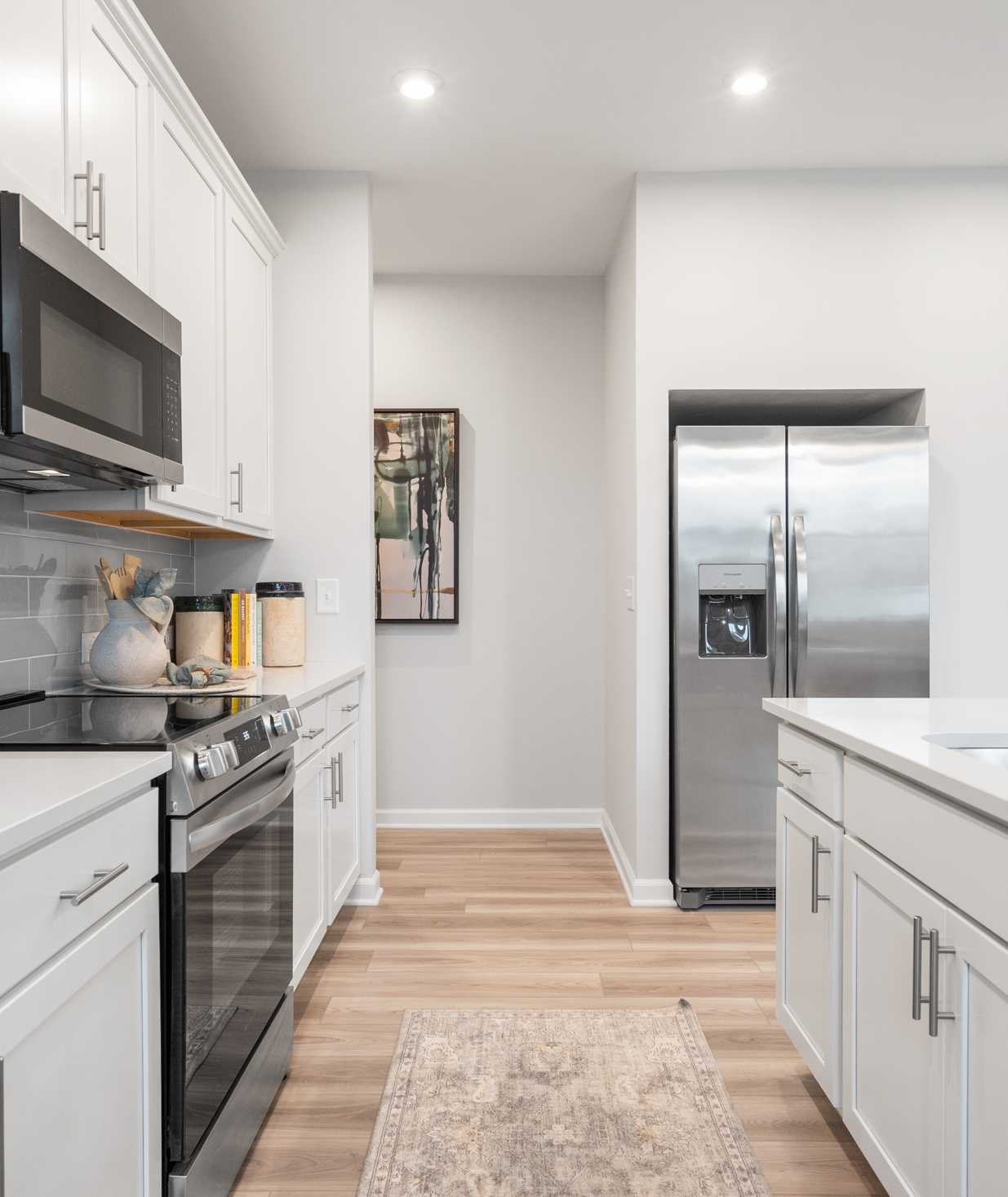 Spacious modern kitchen in Greene Farms Cartersville GA by Davidson Homes with white shaker cabinets, stainless steel appliances, and island