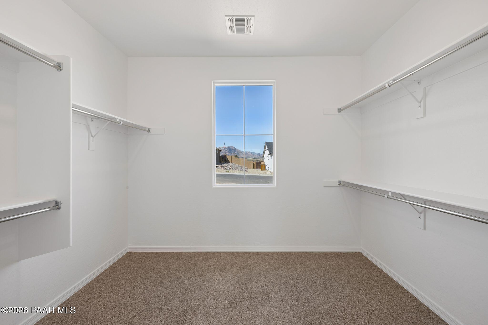 Spacious walk-in closet with built-in shelves, hanging rods, and mountain-view window in Davidson Homes The Monarch A, Prescott, AZ