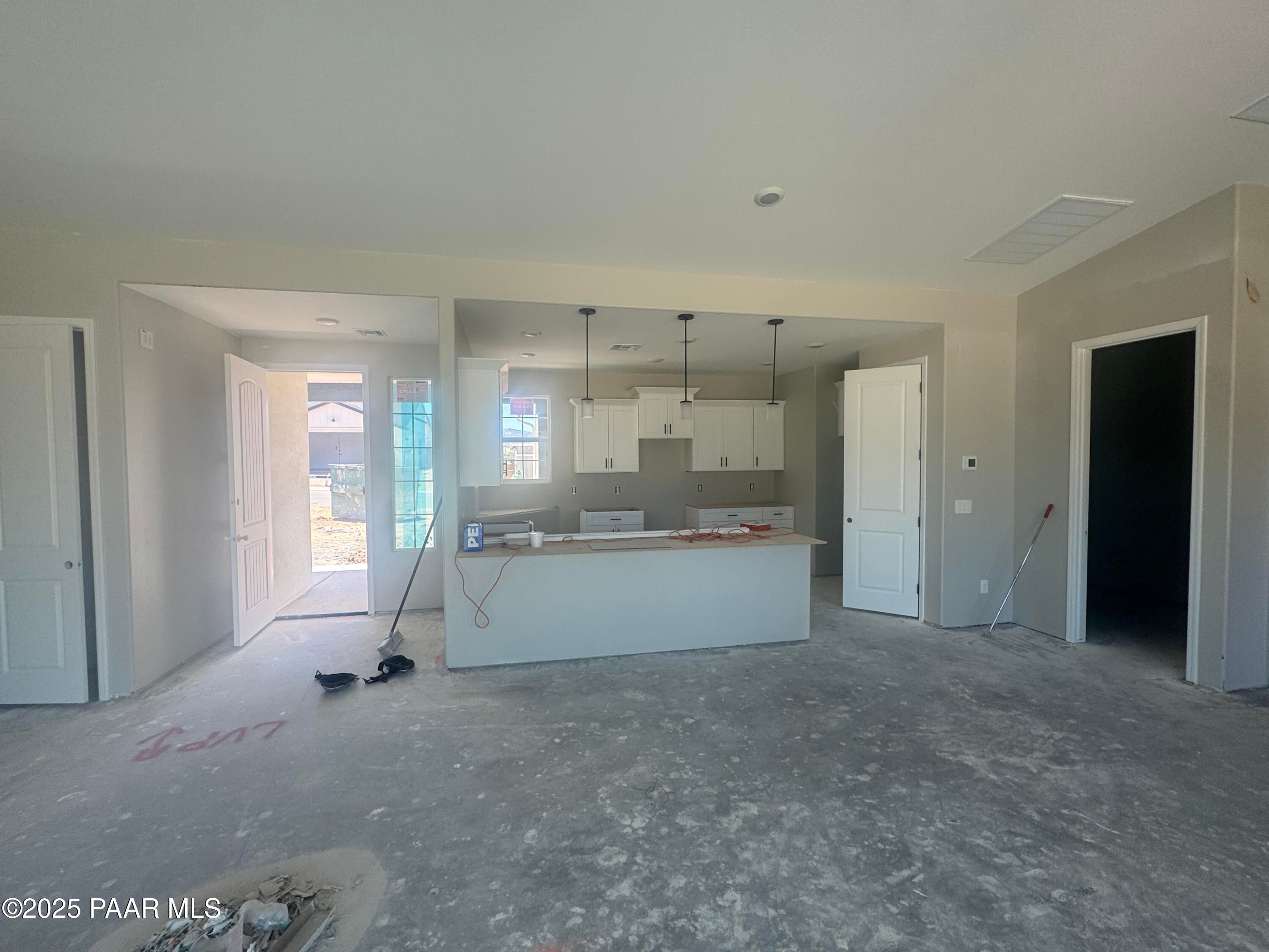 Open-concept great room with white kitchen cabinets and island in Davidson Homes The Daybreak E, 3-bedroom new construction in Westwood, Prescott, Arizona