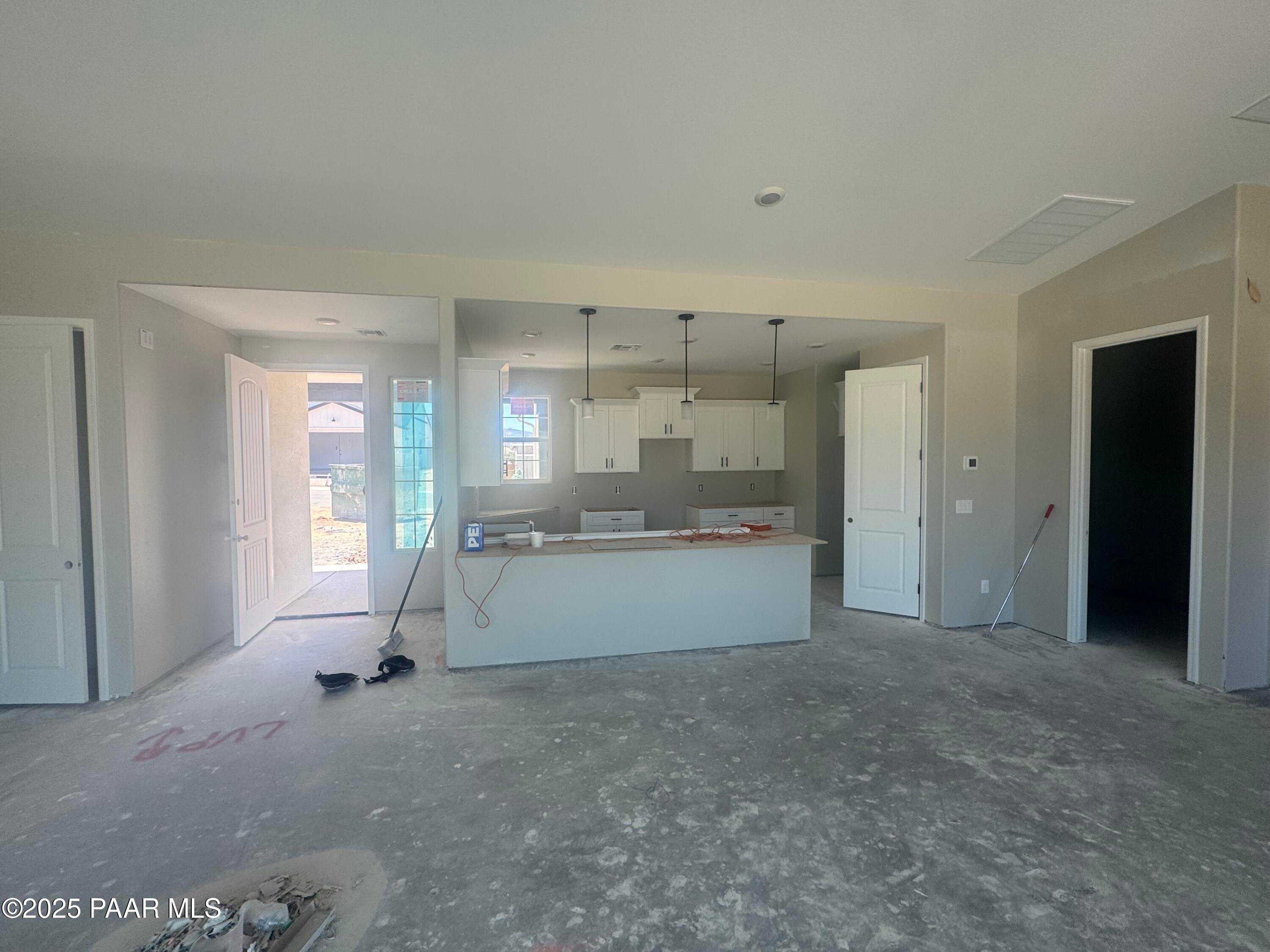 Open-concept great room with white kitchen cabinets and island in Davidson Homes The Daybreak E, 3-bedroom new construction in Westwood, Prescott, Arizona