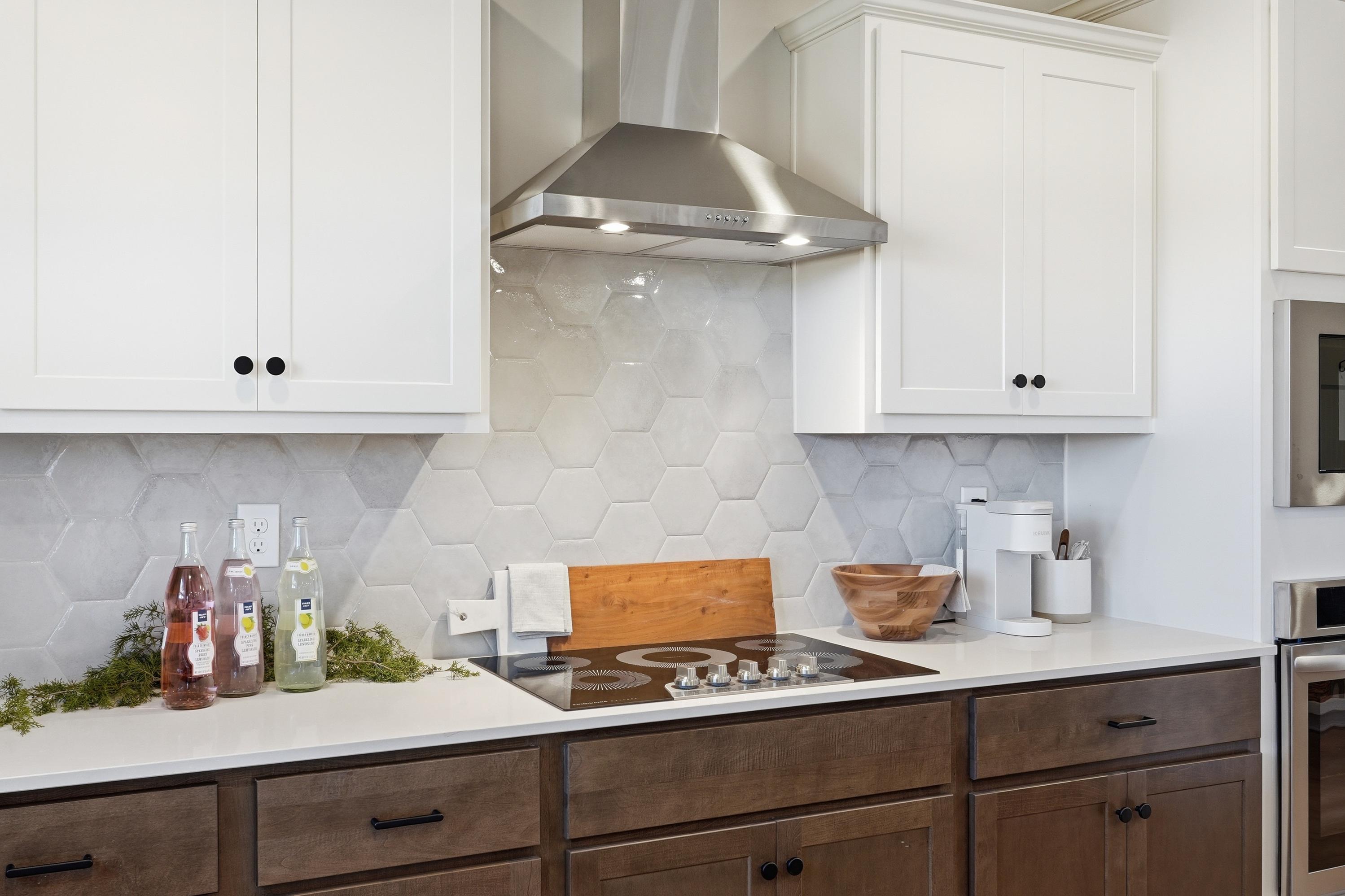 Modern kitchen in Berry Cove New Market Alabama with white upper cabinets, dark wood lowers, hexagonal tile backsplash, and gas cooktop