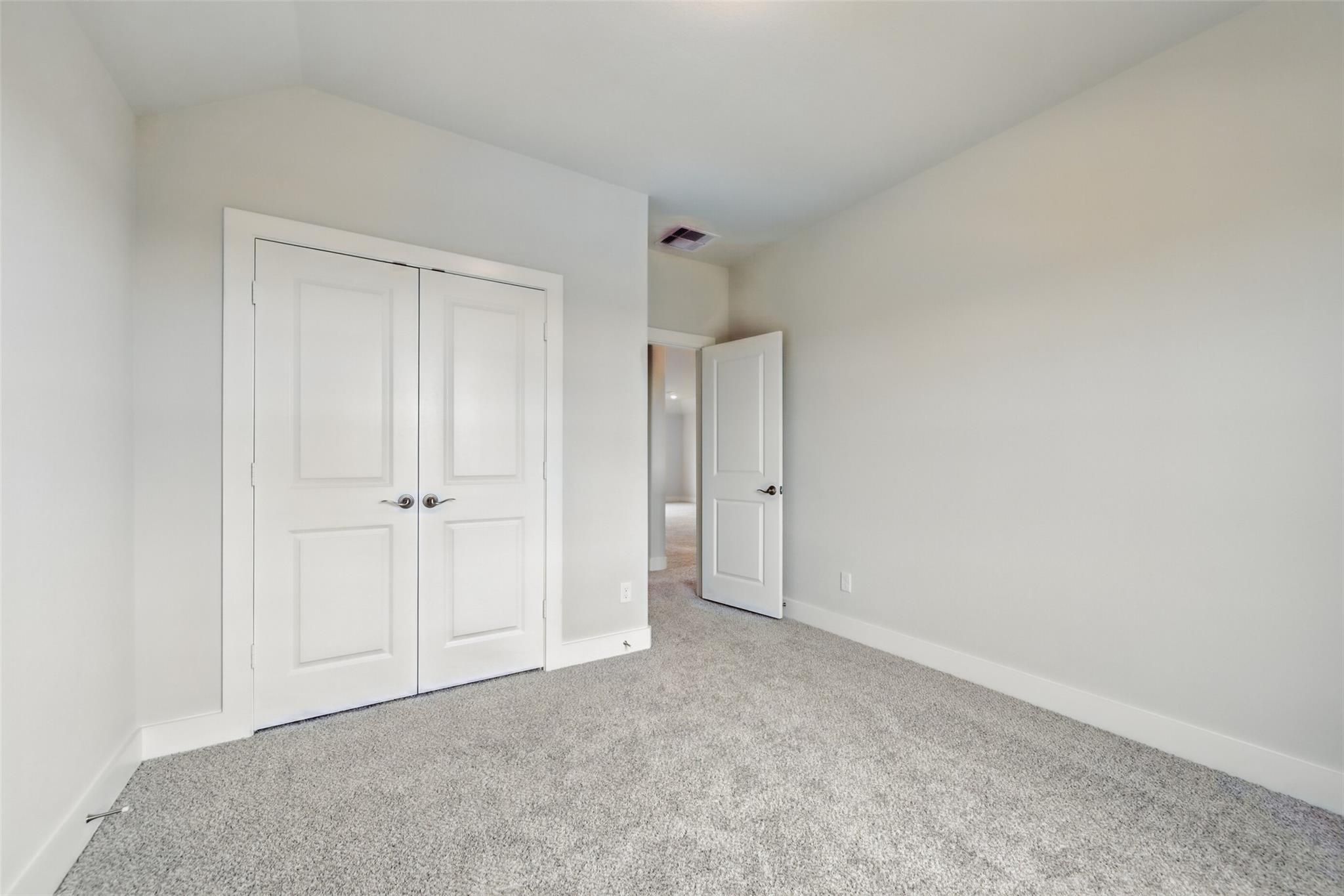 Bright secondary bedroom with white double closet doors and adjacent bath access in Davidson Homes The Philip A, Texas City
