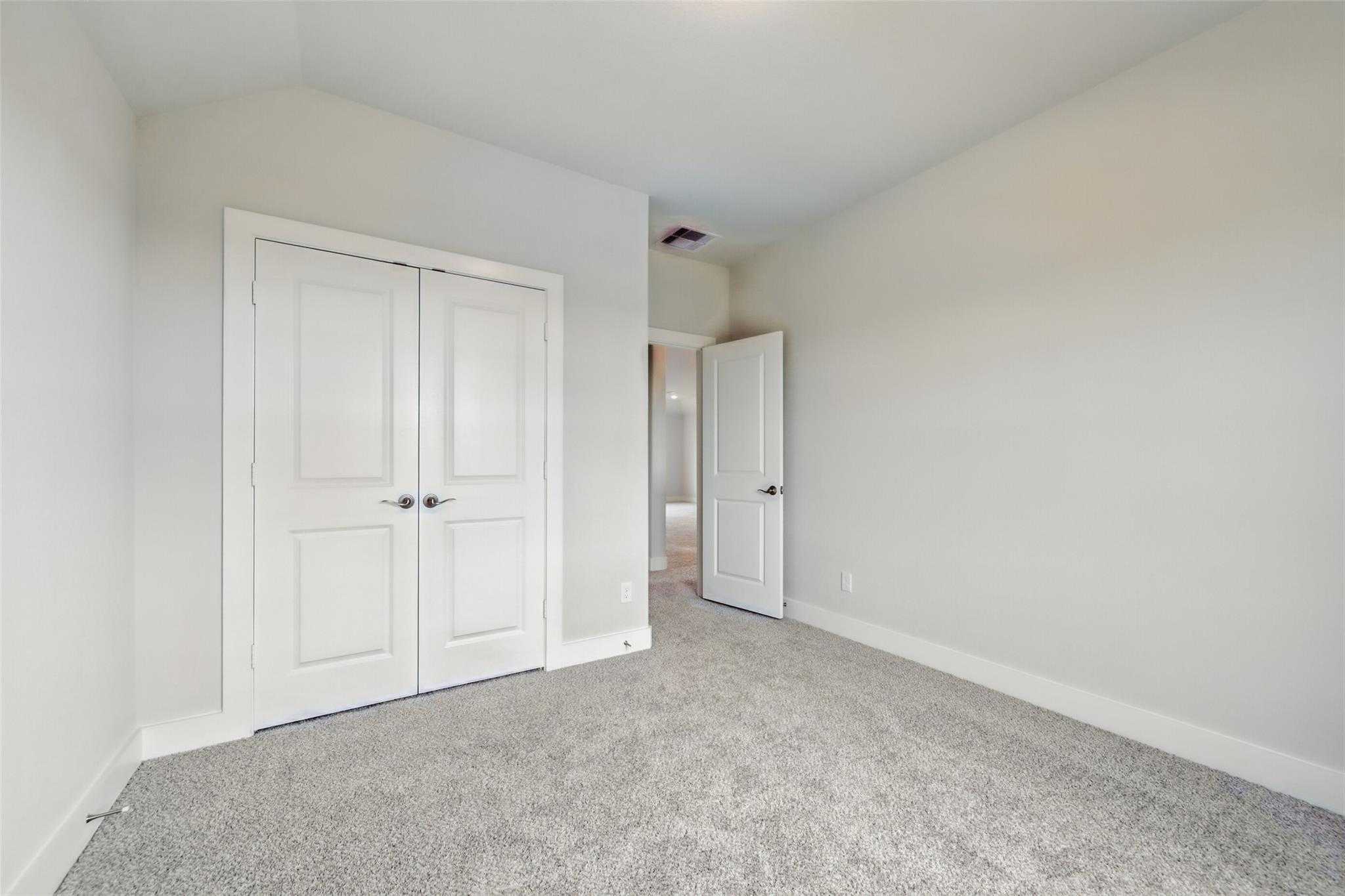 Bright secondary bedroom with white double closet doors and adjacent bath access in Davidson Homes The Philip A, Texas City