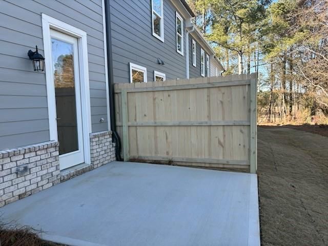 Gray two-story home exterior with glass side door, wooden privacy fence, and concrete patio in Lake Shore, Winder, Georgia
