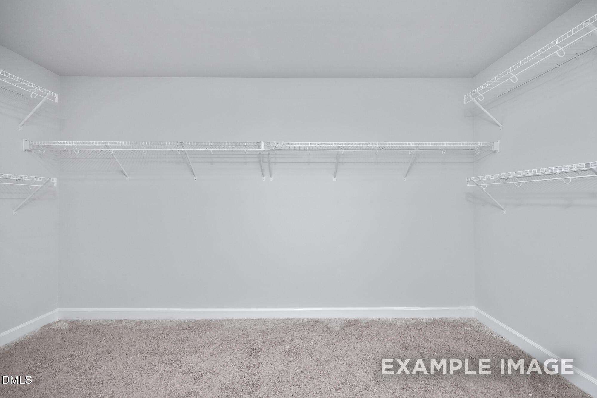 Spacious walk-in closet with white wire shelving and gray carpet in Davidson Homes The Hickory II B, Lillington, NC