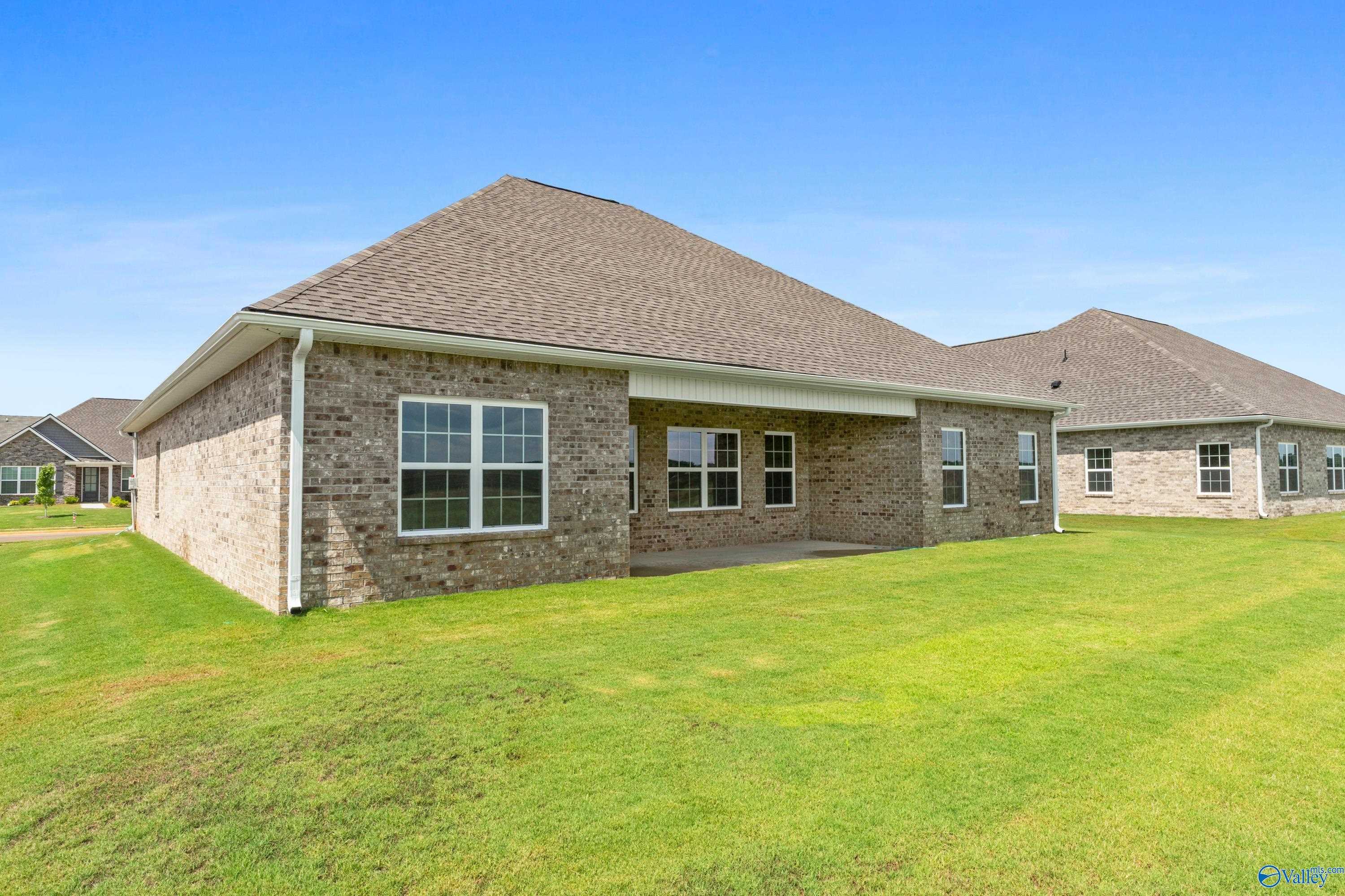 Single-story brick home with covered patio, large windows, and lush green lawn in Kendall Farms, Toney, Alabama - Davidson Homes Rockford B