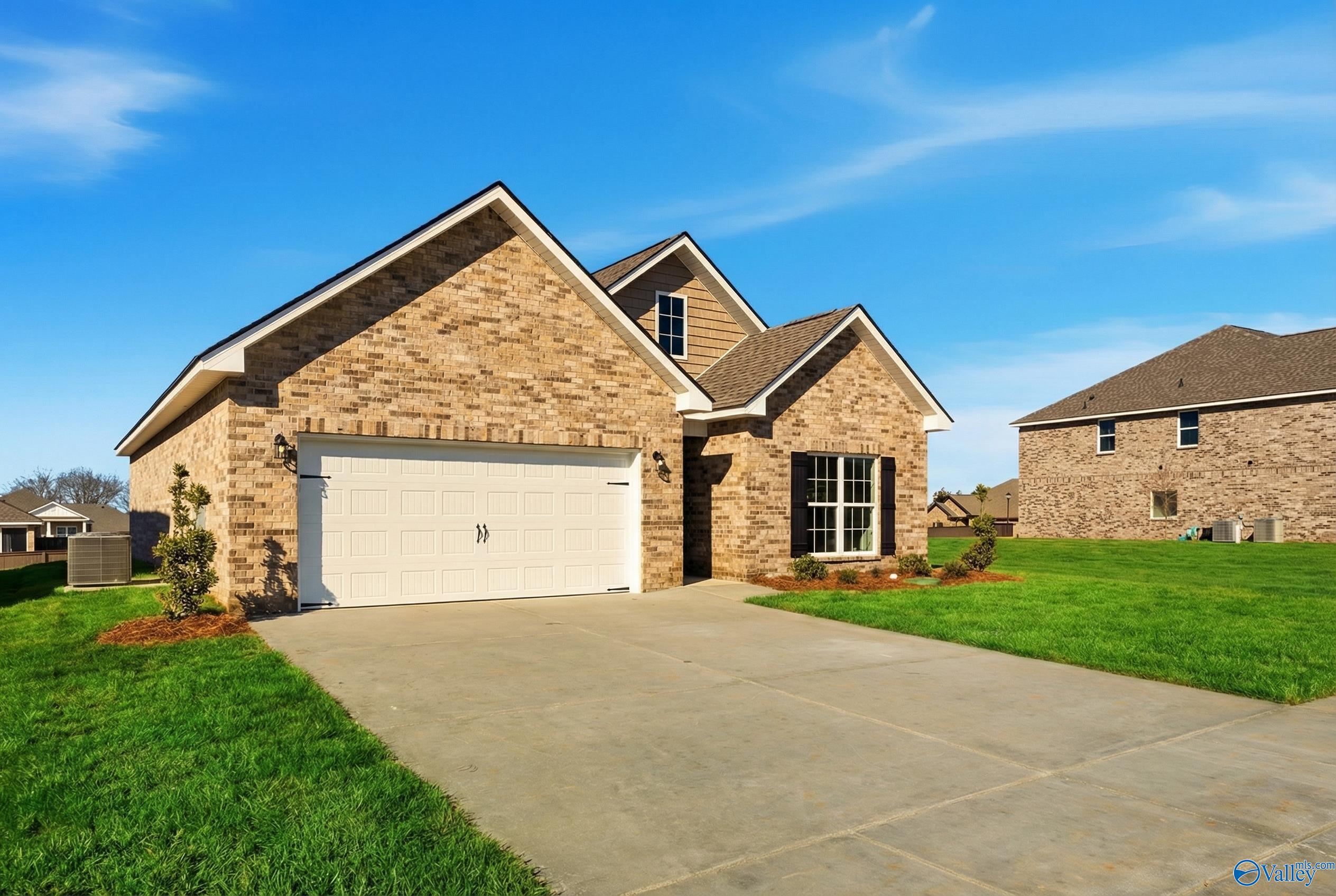 Brick single-story home with tan facade, 2-car garage, driveway, and lush green lawn in Creek Grove, New Market, Alabama